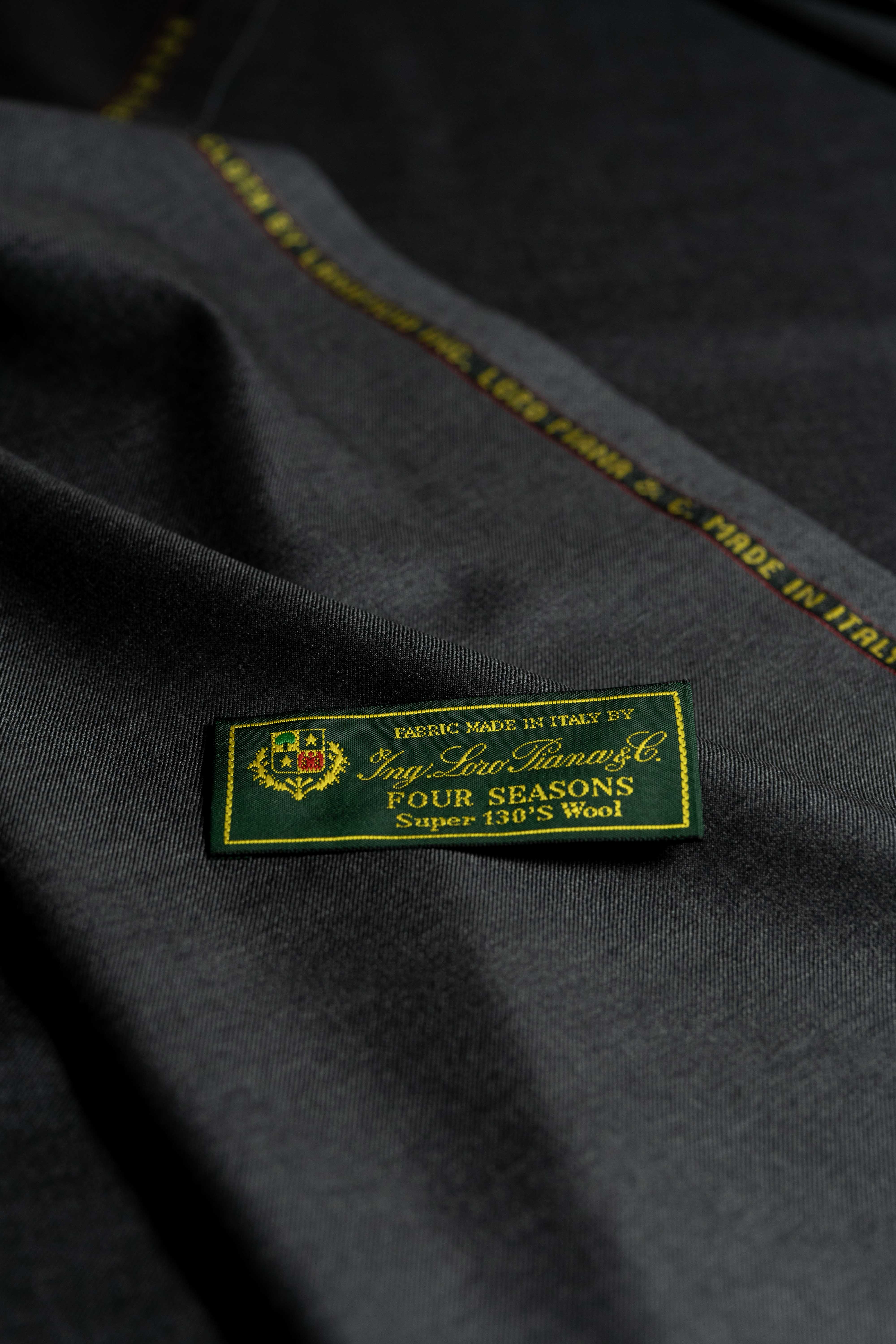 Loro Piana Charcoal 130's Merino Wool Suit Fabric with Four Seasons label, highlighting quality and luxury tailoring.