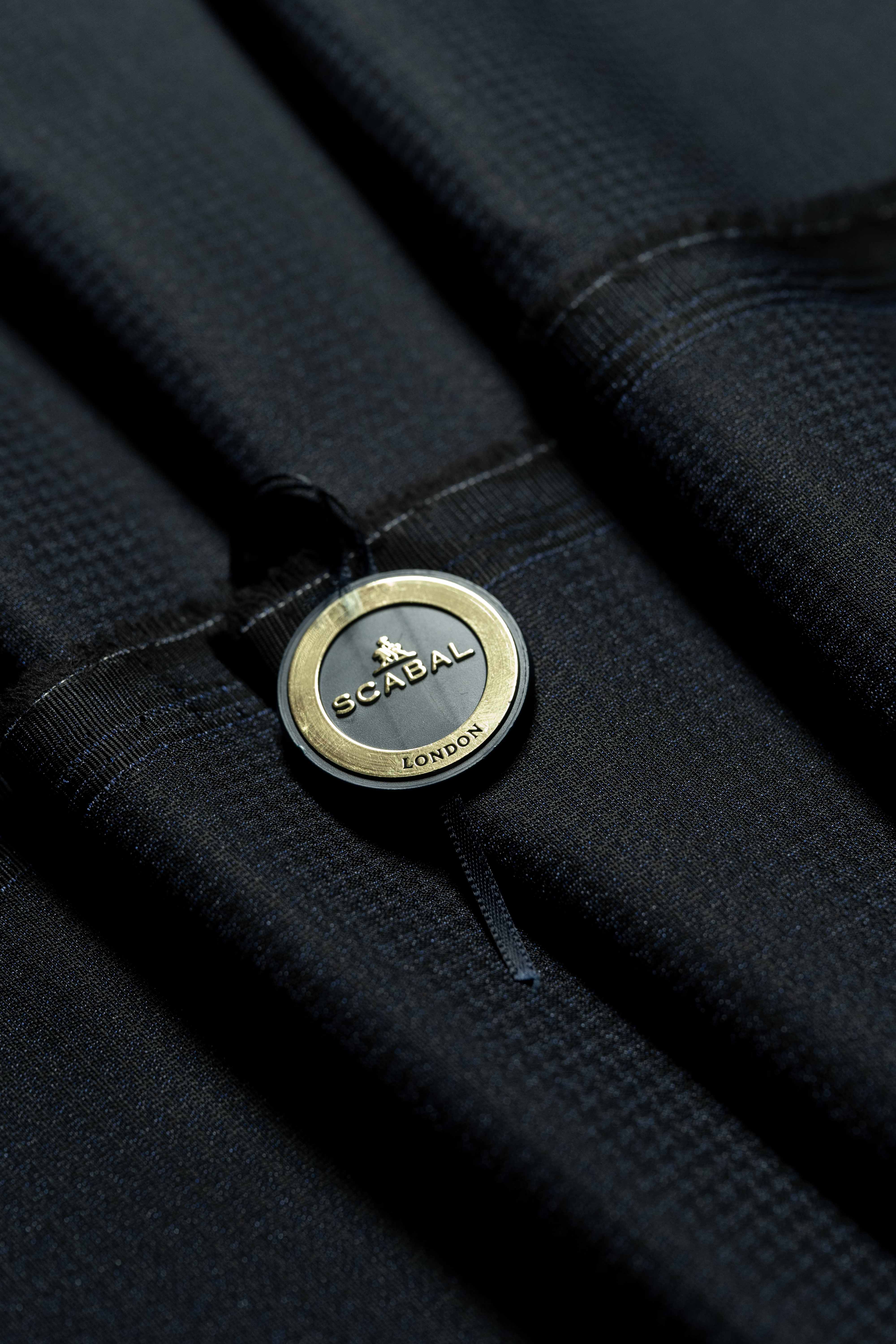 Close-up of Scabal button on dark navy fabric, showcasing luxury and quality in tailoring.