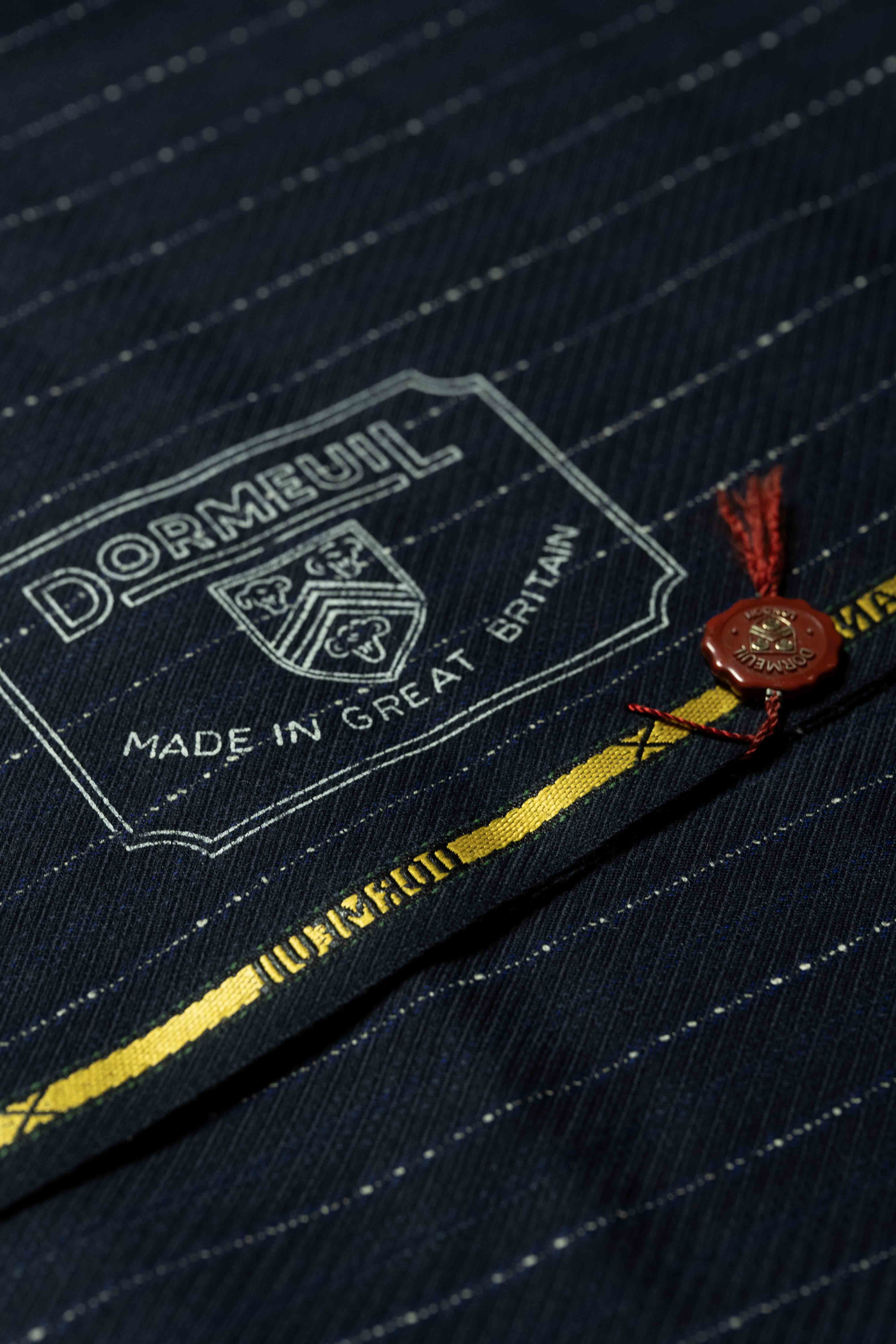 Dormeuil logo on blue and white striped wool suiting fabric, showcasing quality craftsmanship and British origin.
