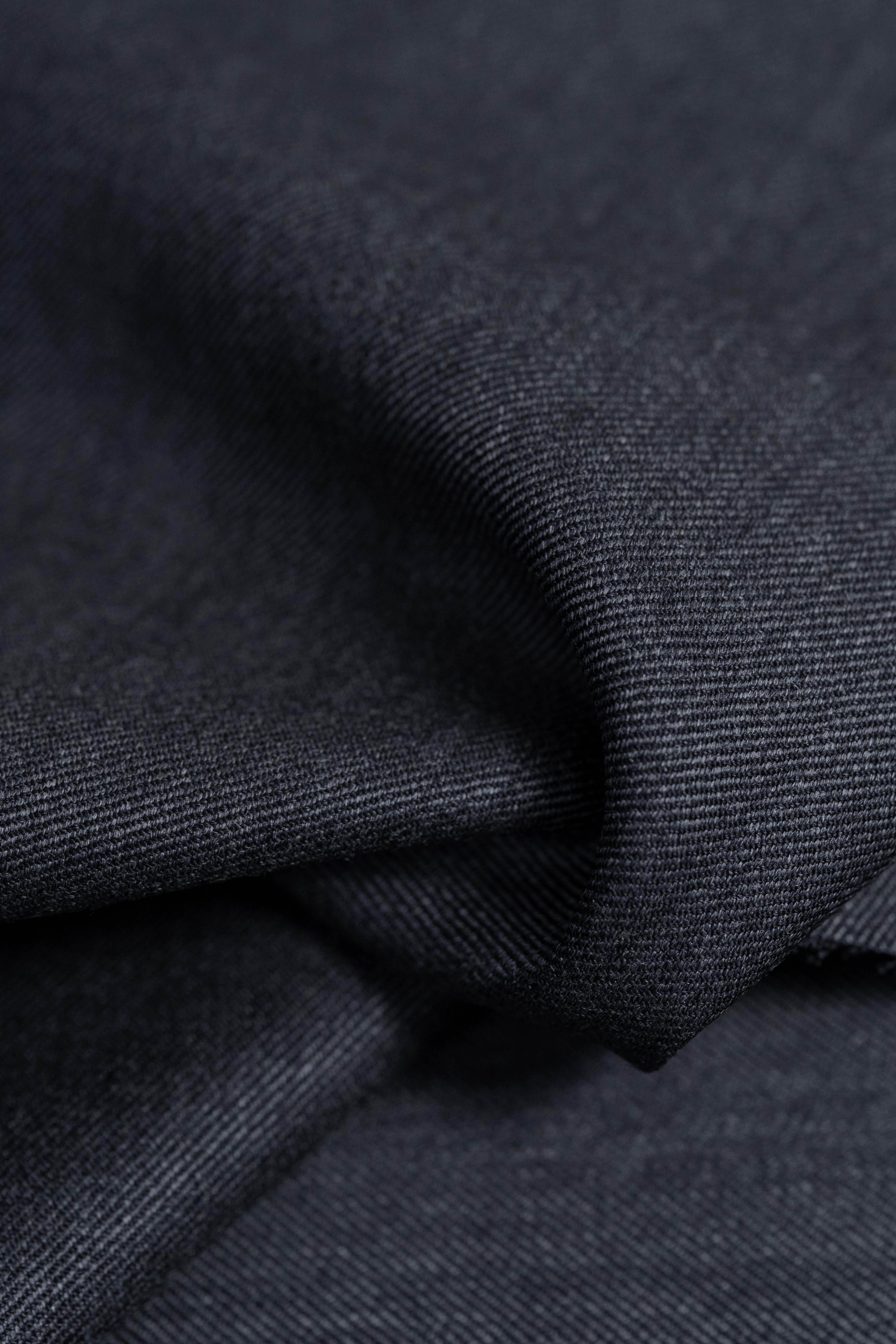 Close-up of dark grey Super 100s wool suiting fabric with soft sheen and diagonal weave.