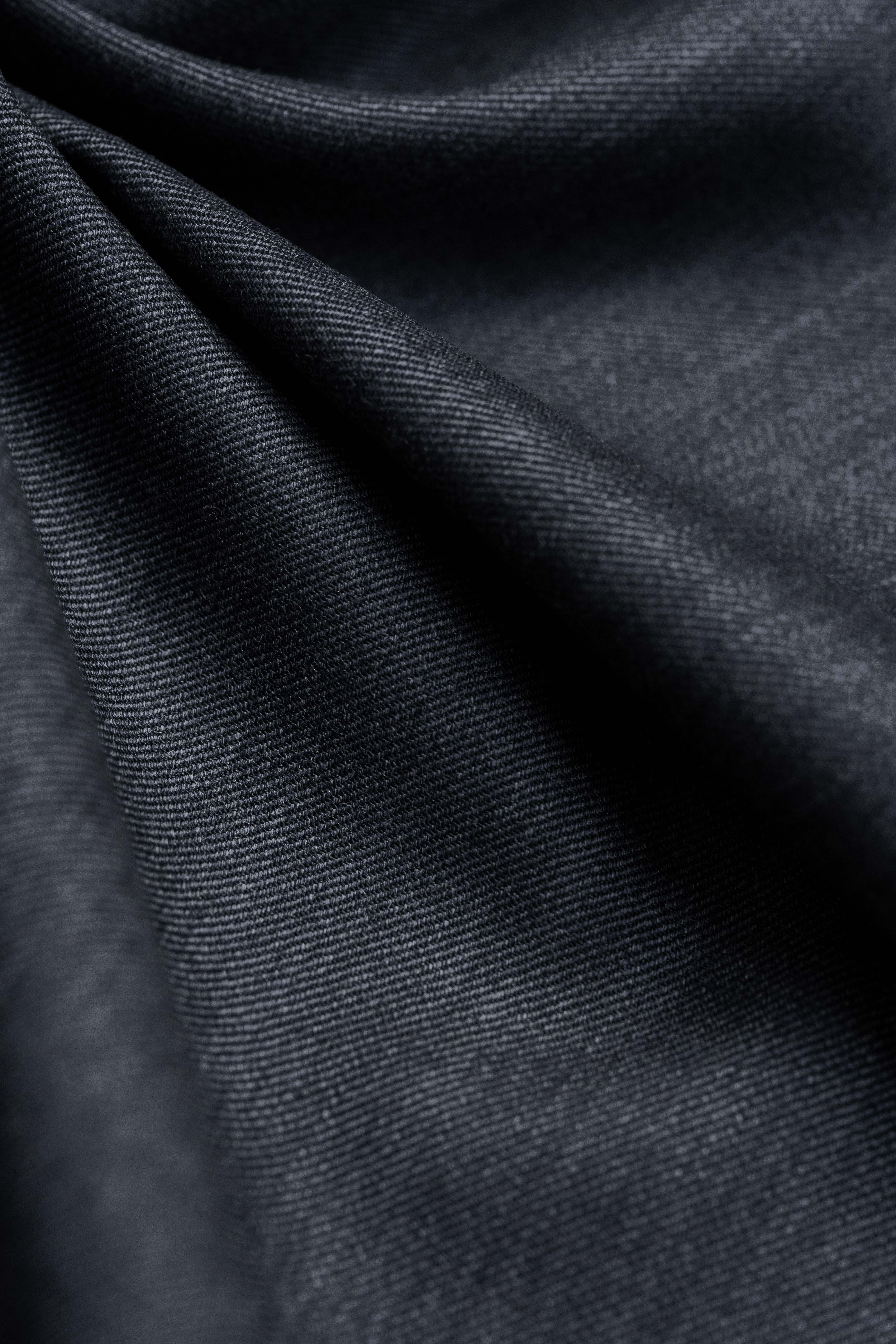 Close-up of dark grey Super 100s wool suiting fabric showcasing its soft sheen and drape.