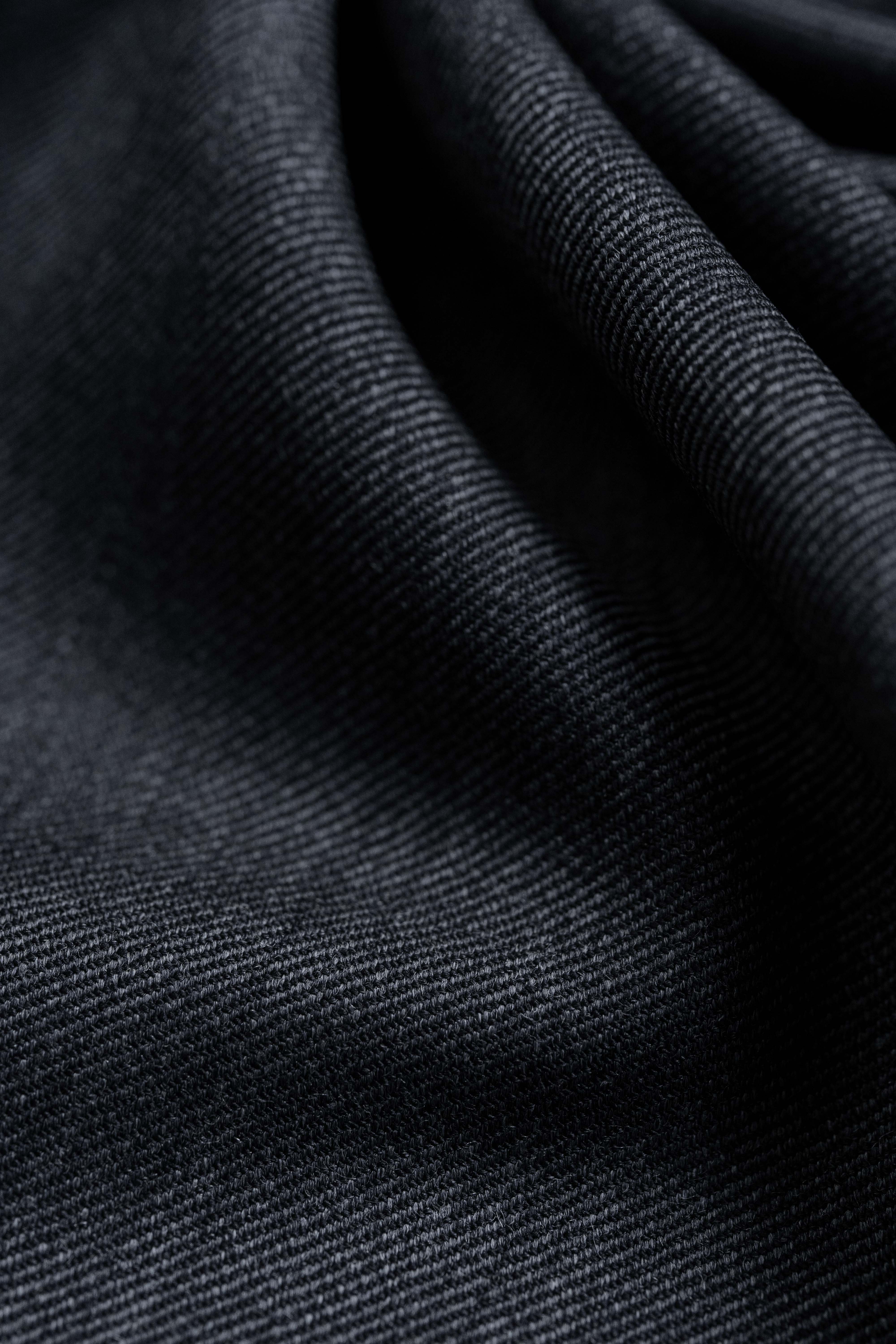 Close-up of dark grey Super 100s wool suiting fabric showcasing a soft sheen and diagonal weave.