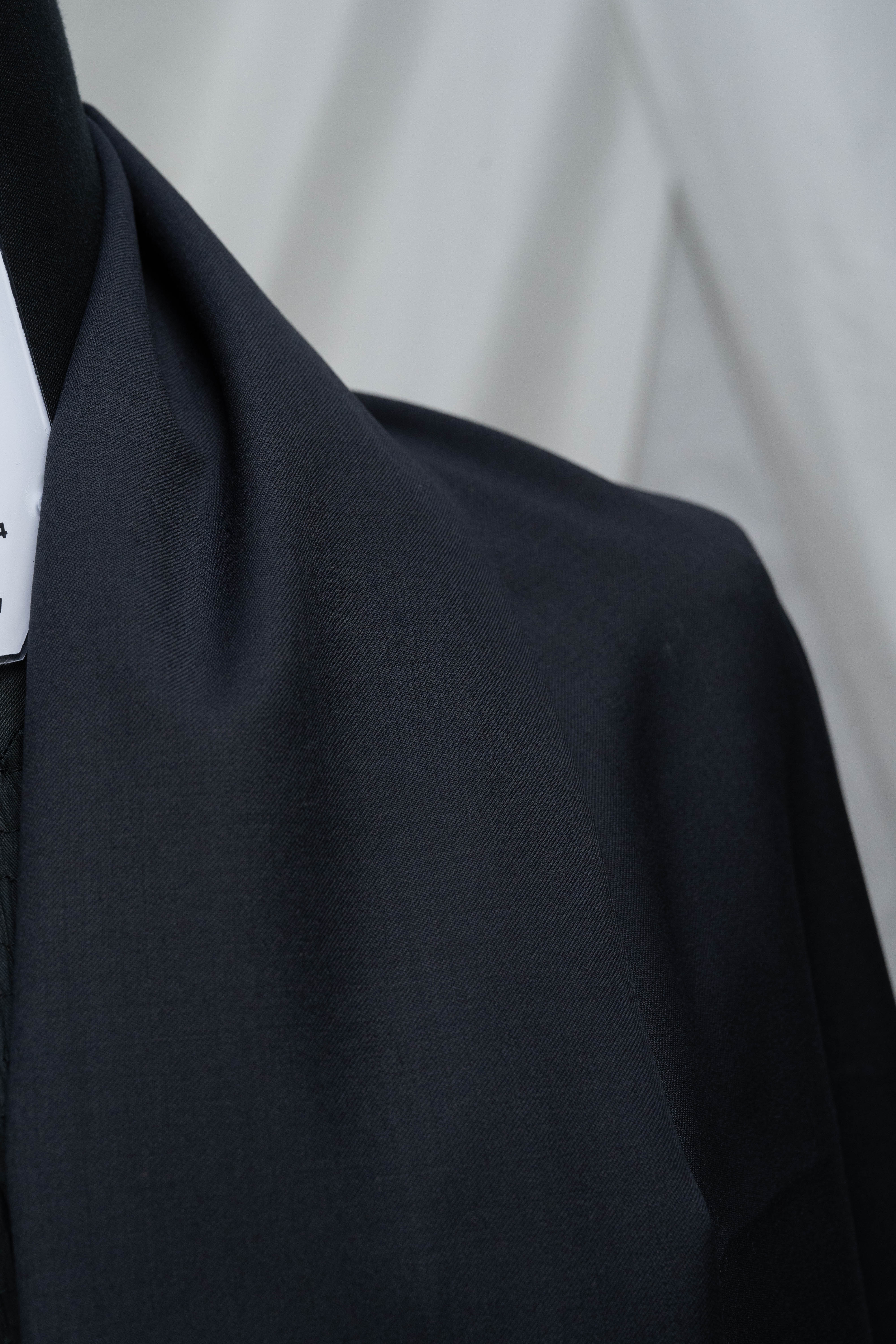 England Black Super 100's Wool Suiting Fabric draped on a mannequin, showcasing its smooth texture and deep color.