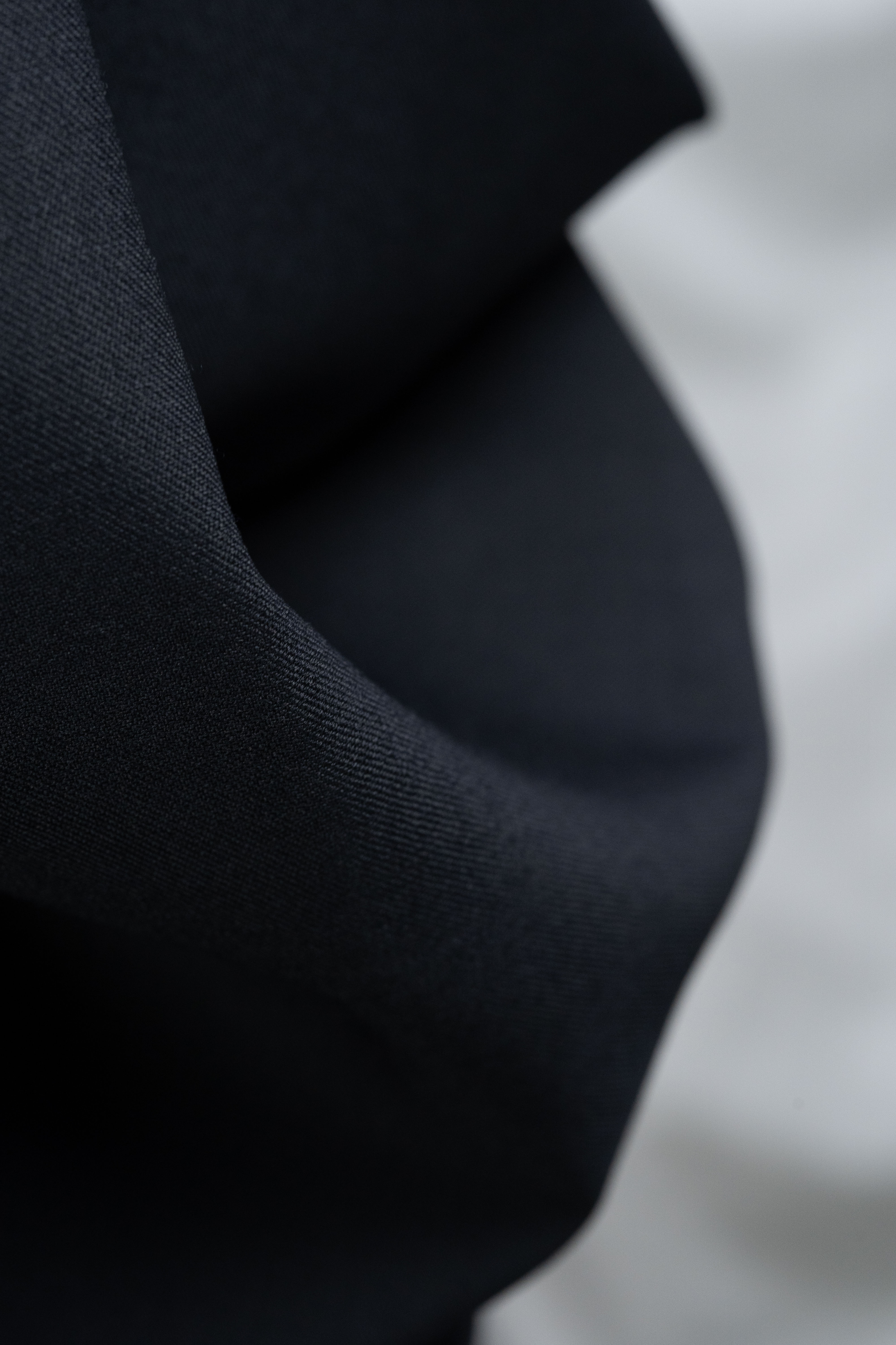 England Black Super 100's Wool Suiting Fabric texture in close-up, showcasing luxurious black material.