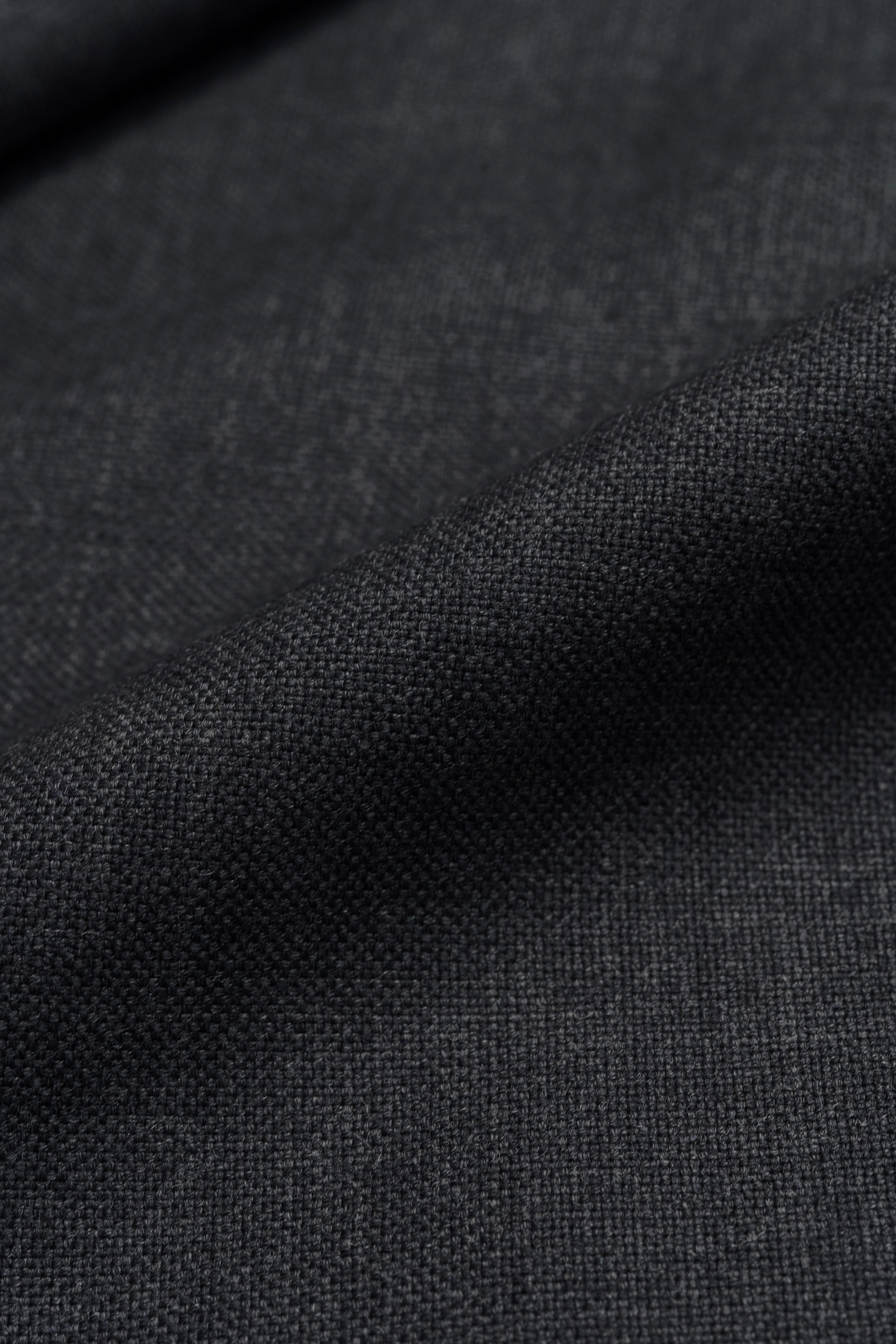 Close-up view of Groves & Lindley dark grey wool suit fabric, showcasing its texture and quality.