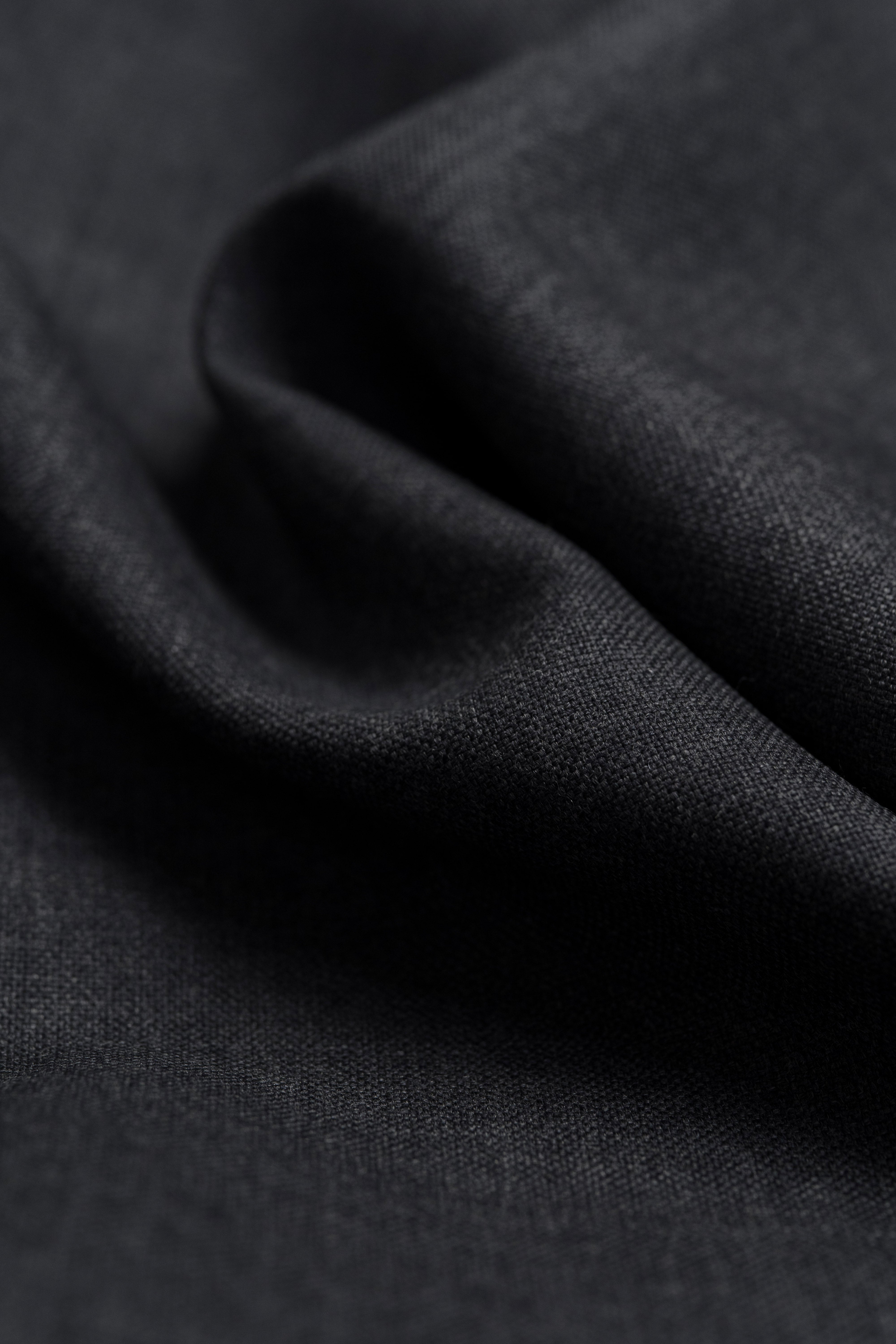 Close-up of dark grey wool suit fabric, showcasing its smooth texture and fine weave.