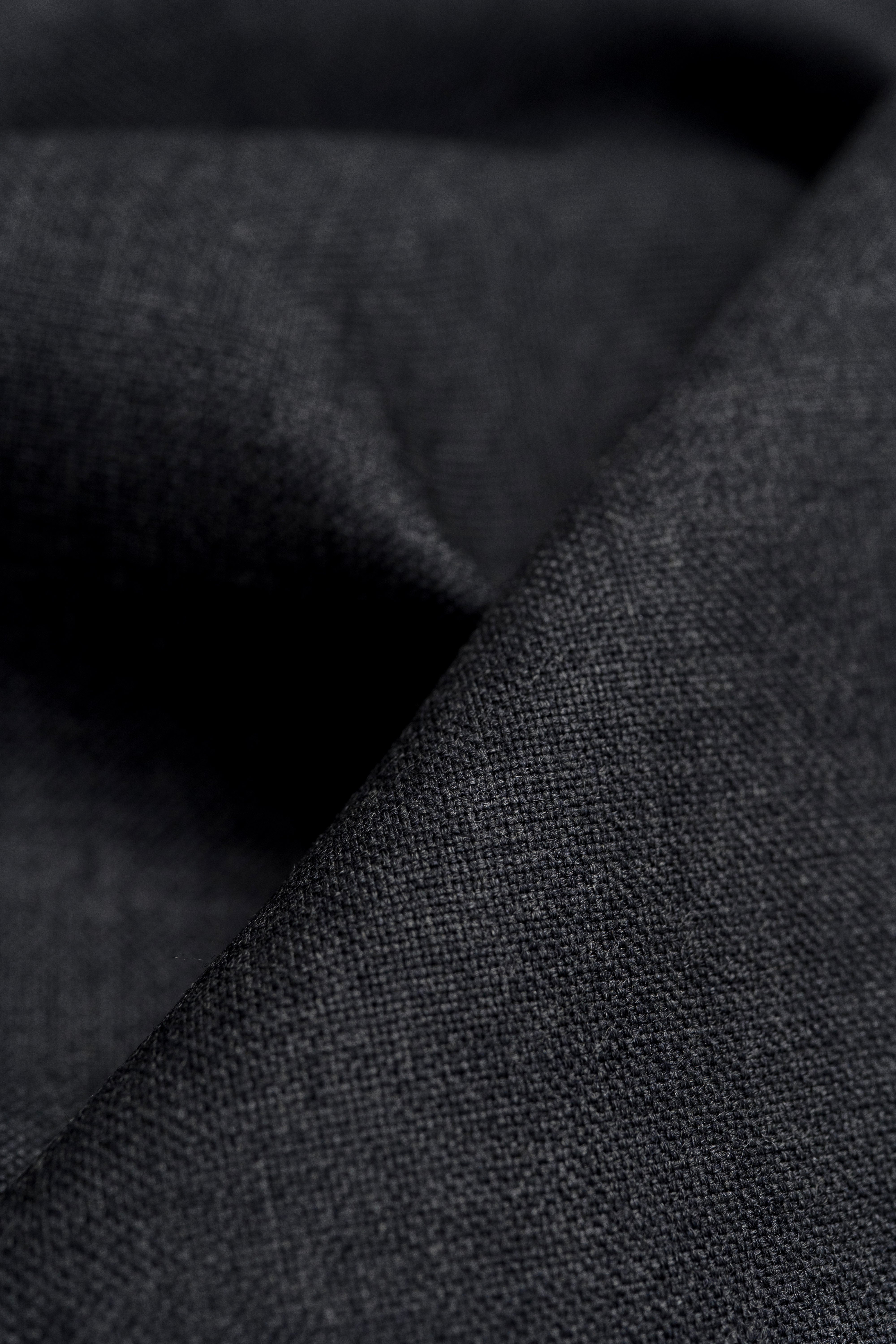 Close-up of Groves & Lindley dark grey wool suit fabric, showing the texture and quality of the material.