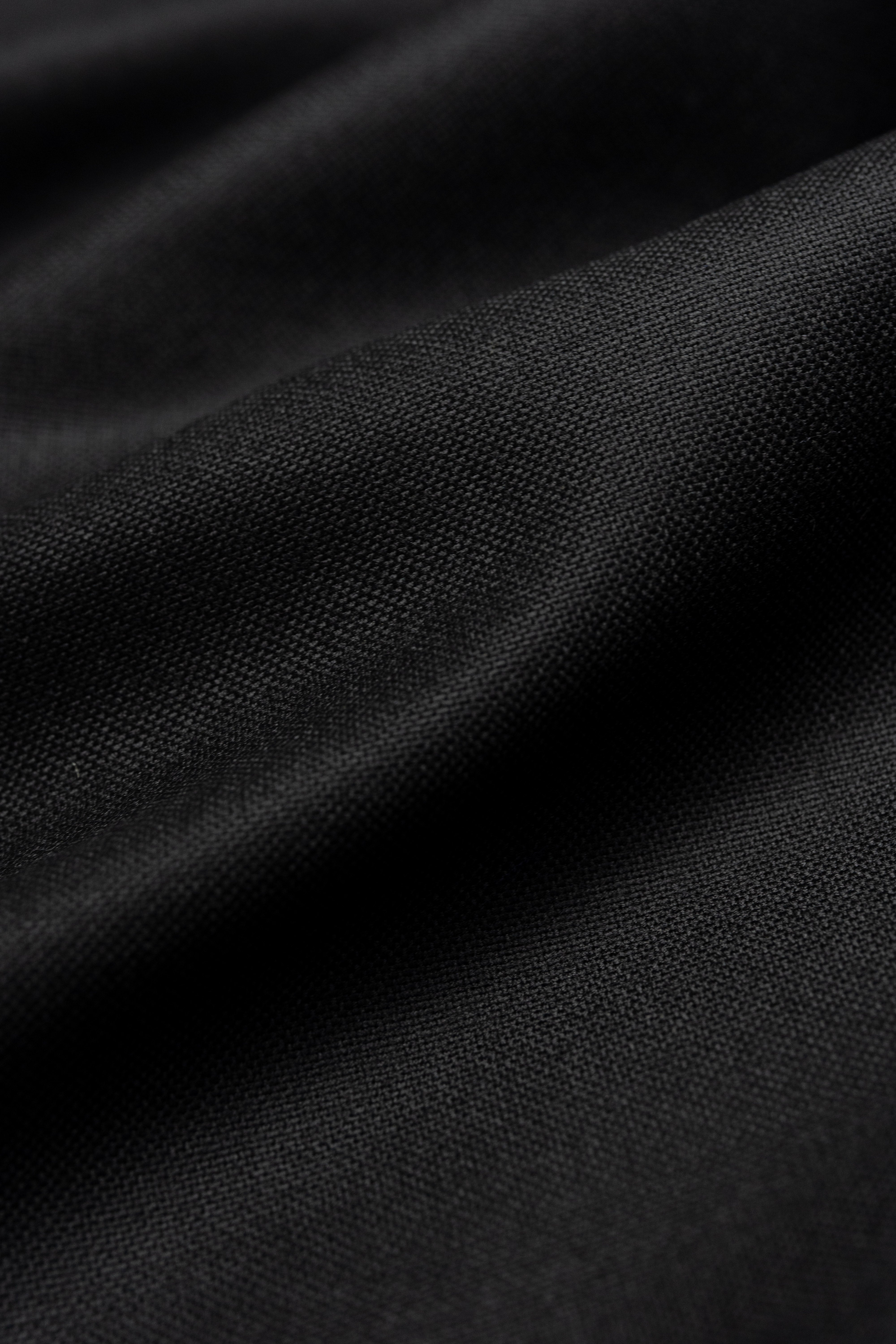 Groves & Lindley plain worsted black wool suit fabric texture close-up.