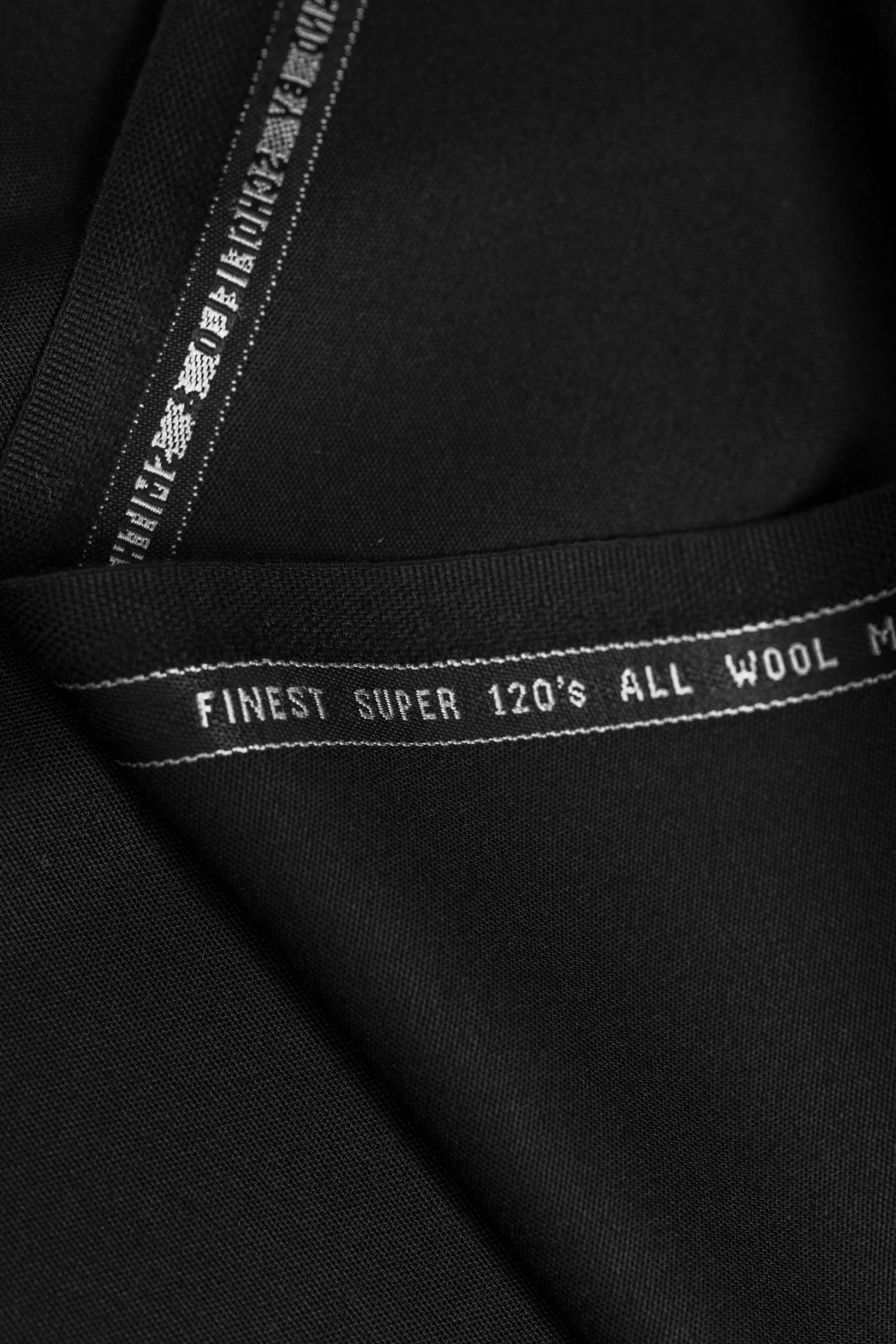 Close-up of Groves & Lindley Super 120's worsted plain black wool suit fabric showing fine texture.