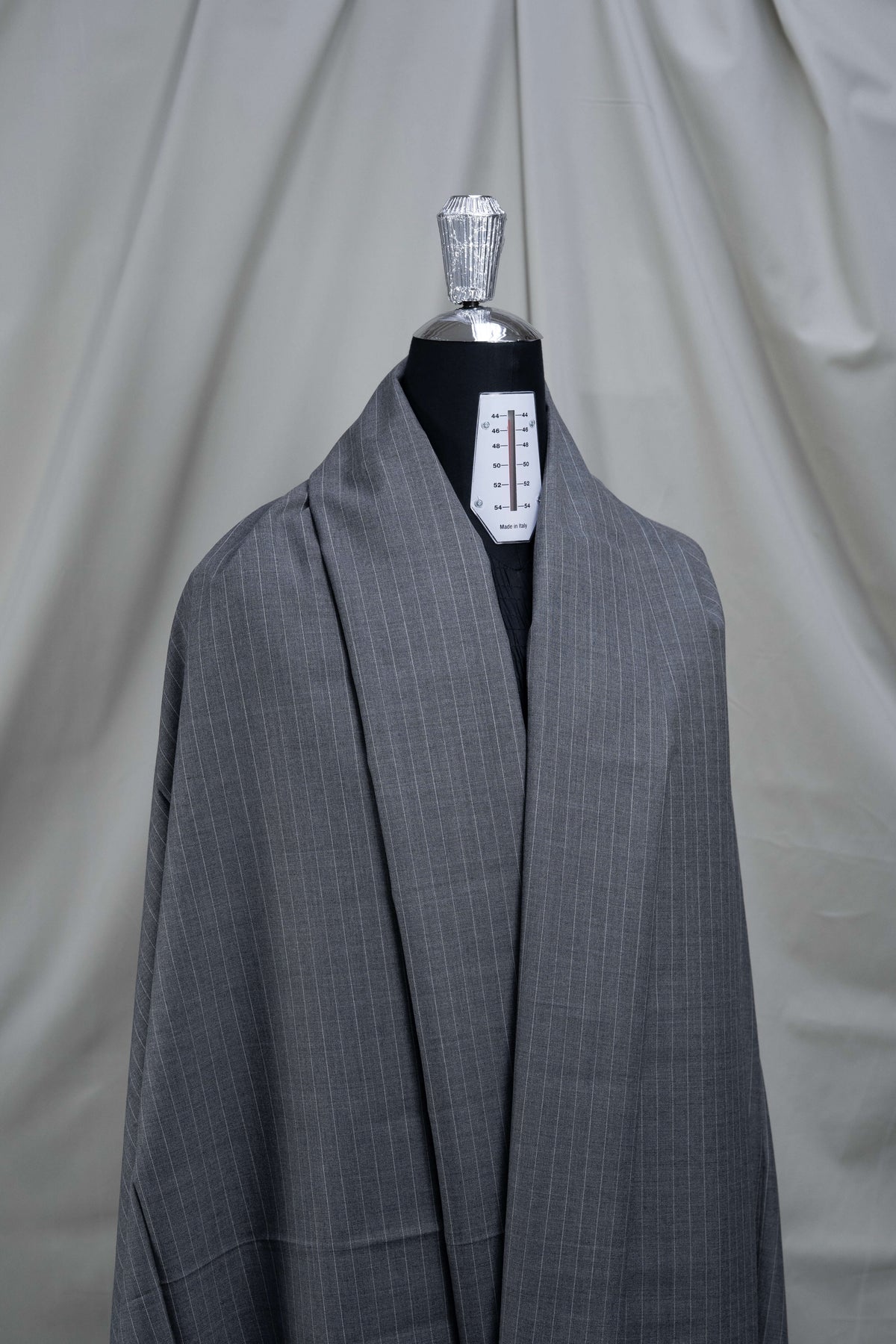 Grey stripe wool suiting fabric displayed on a dress form, showcasing its classic pattern and durability.