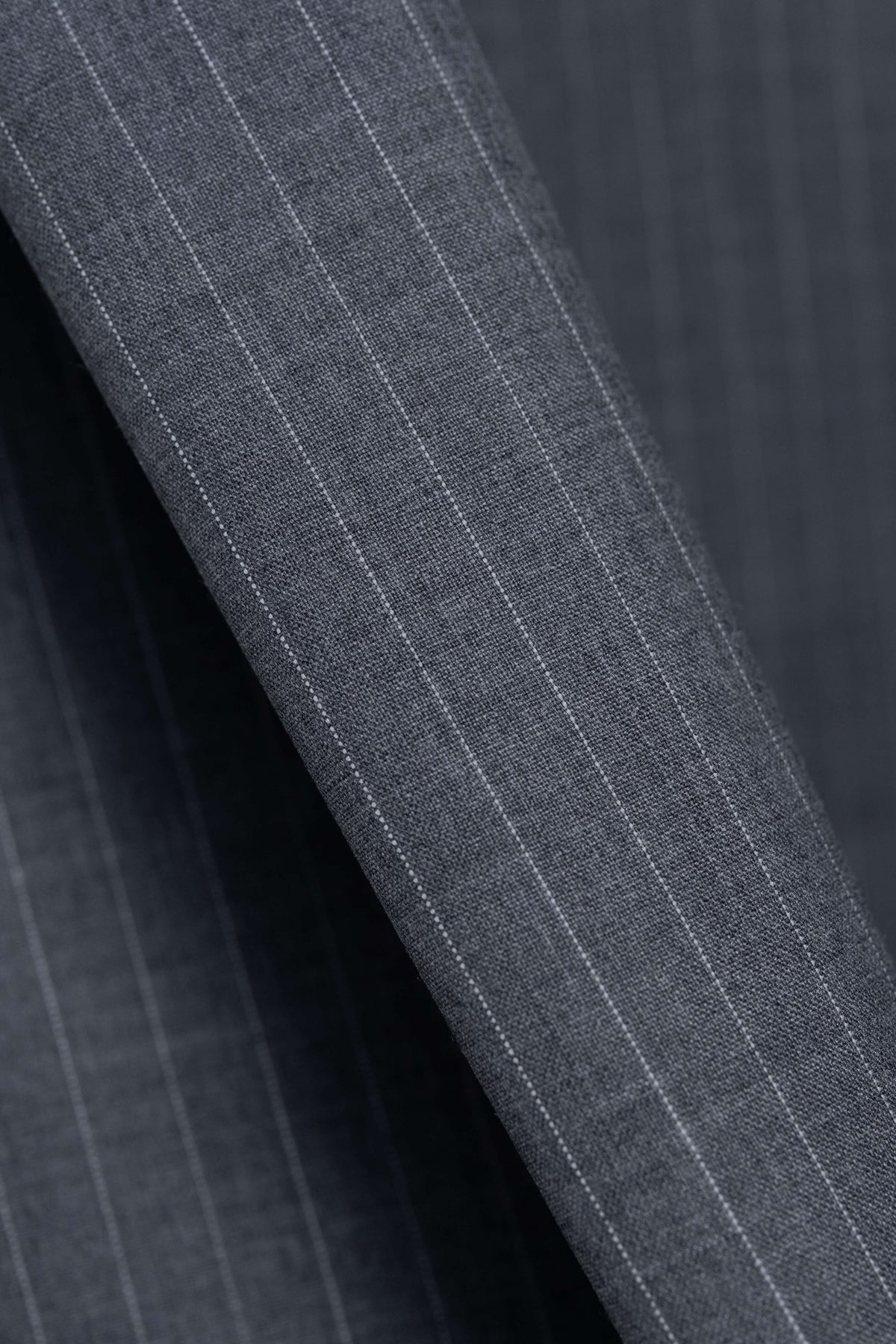 Close-up of grey stripe wool suiting fabric showcasing durable texture and classic pattern for trousers.