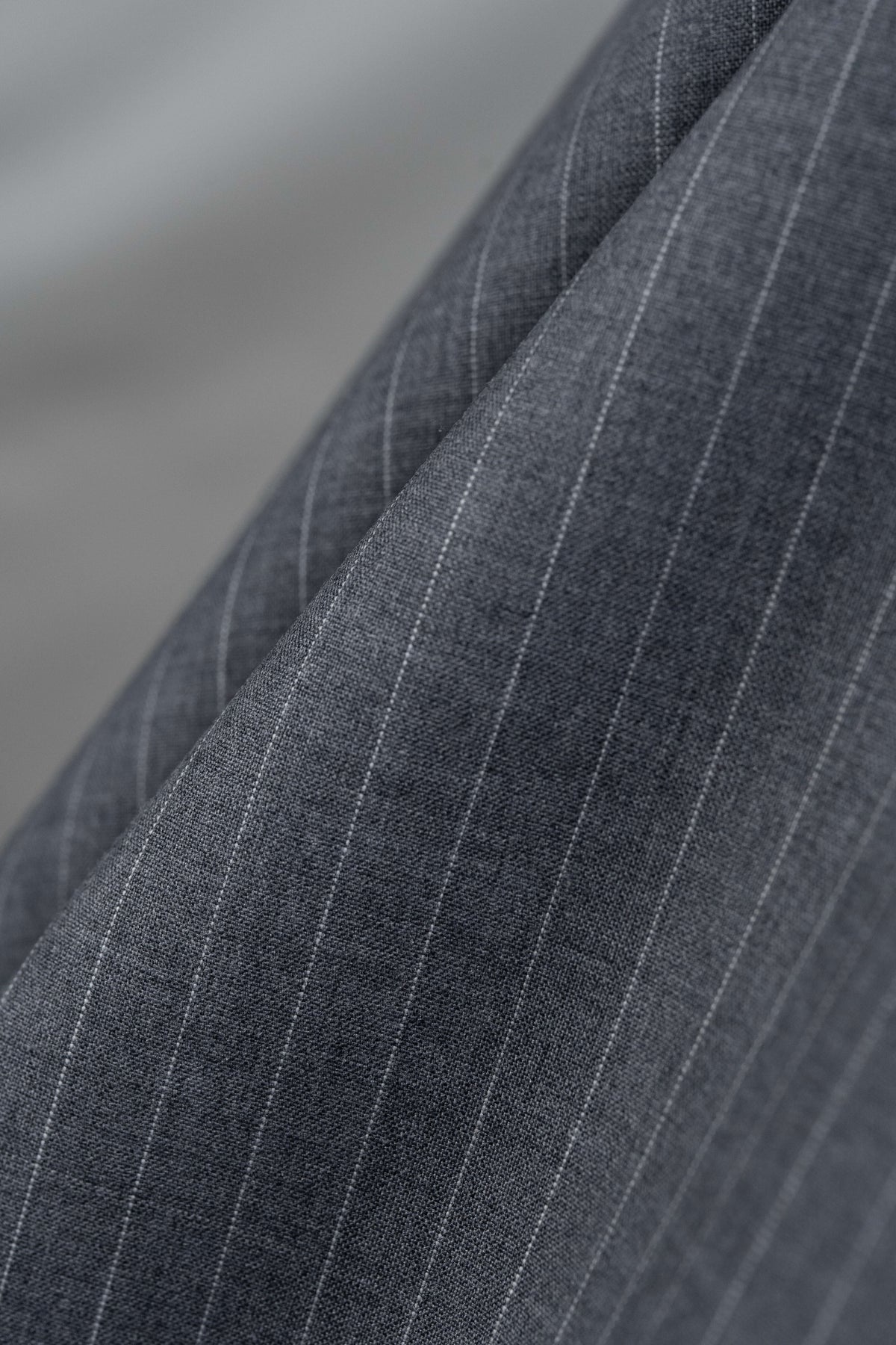 Close-up of grey stripe wool suiting fabric showing a durable and classic pattern for trousers.
