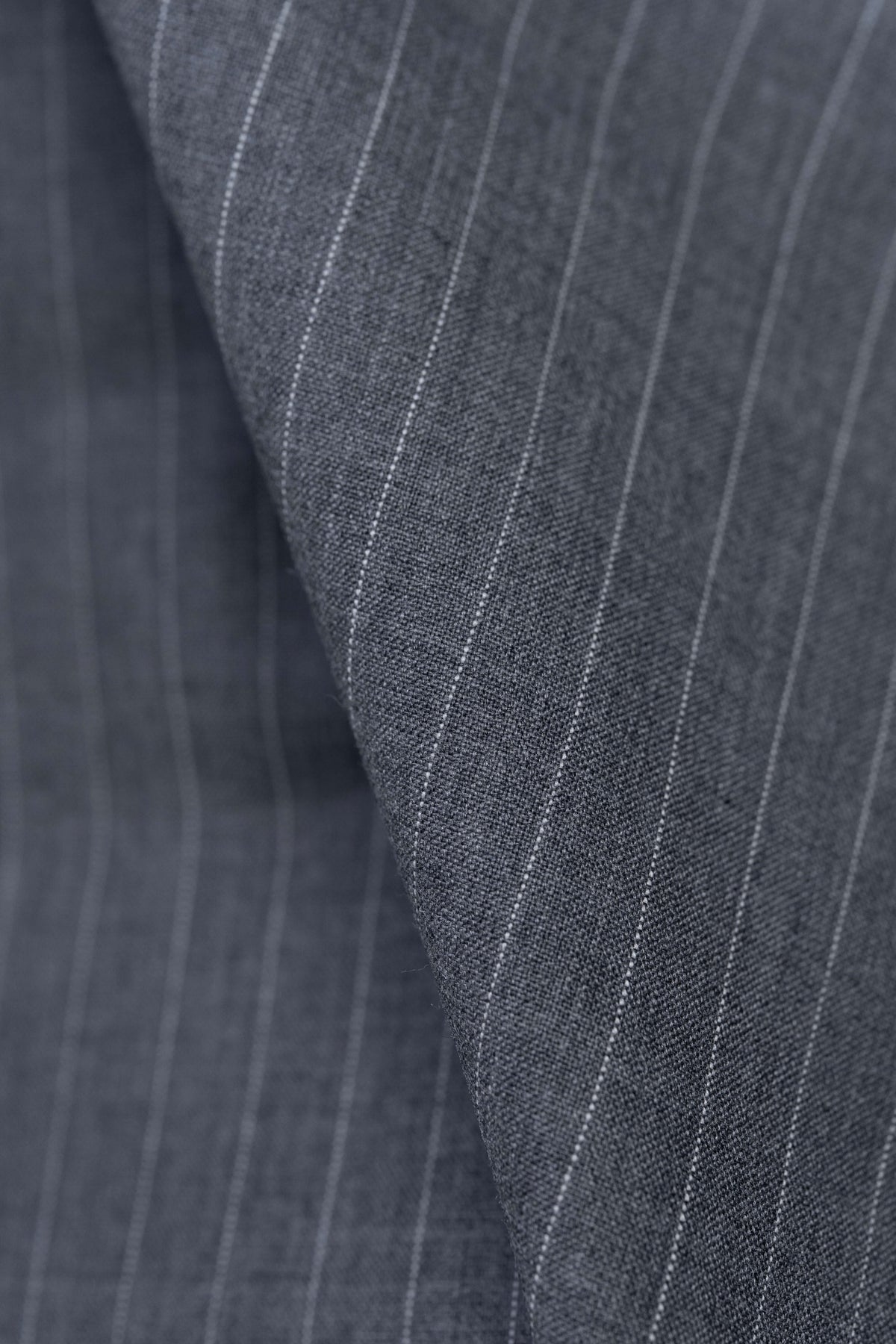 Close-up of grey stripe wool suiting fabric, showcasing texture and durable design for timeless trousers.