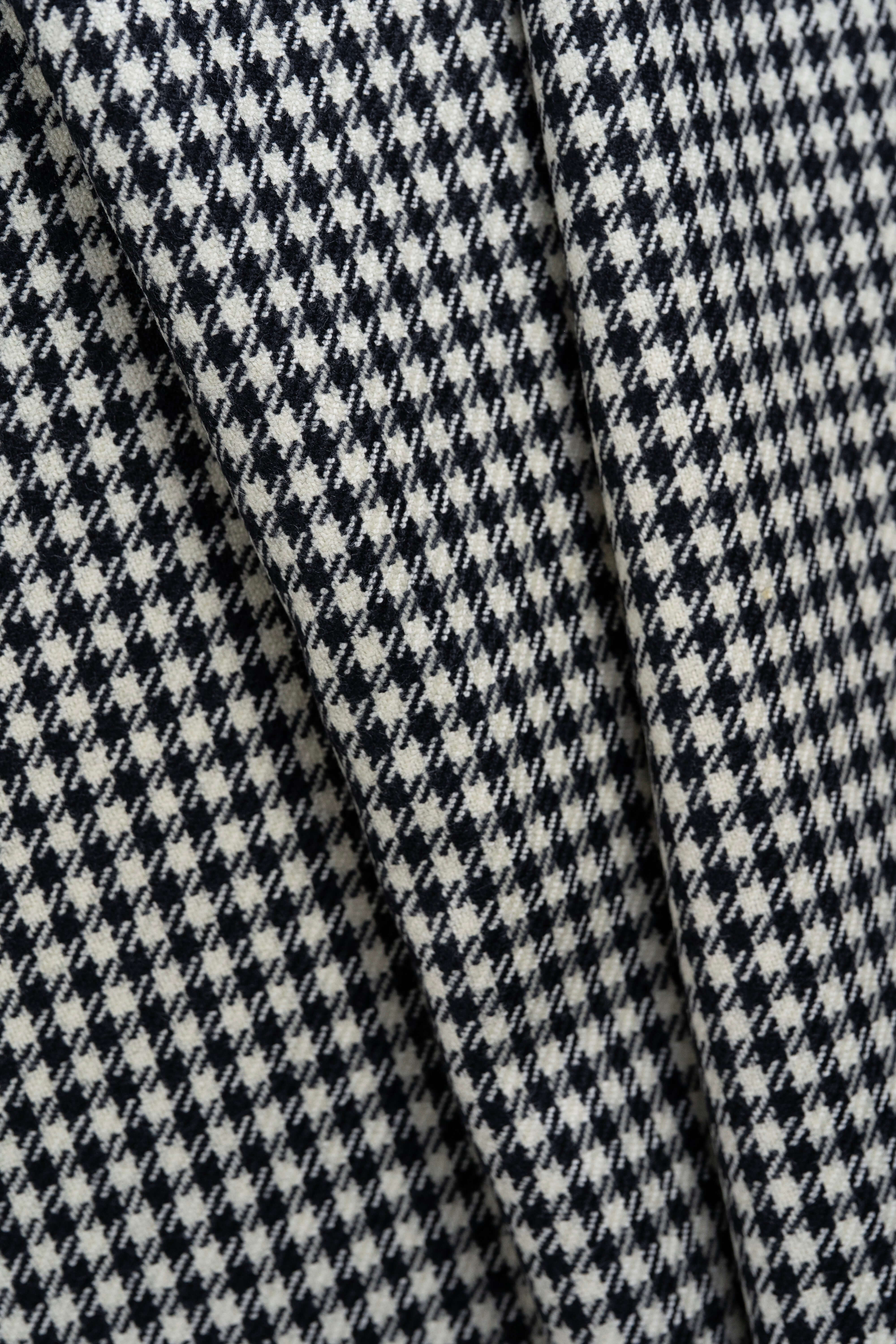 Close-up of houndstooth wool jacketing fabric showing intricate black and white pattern.