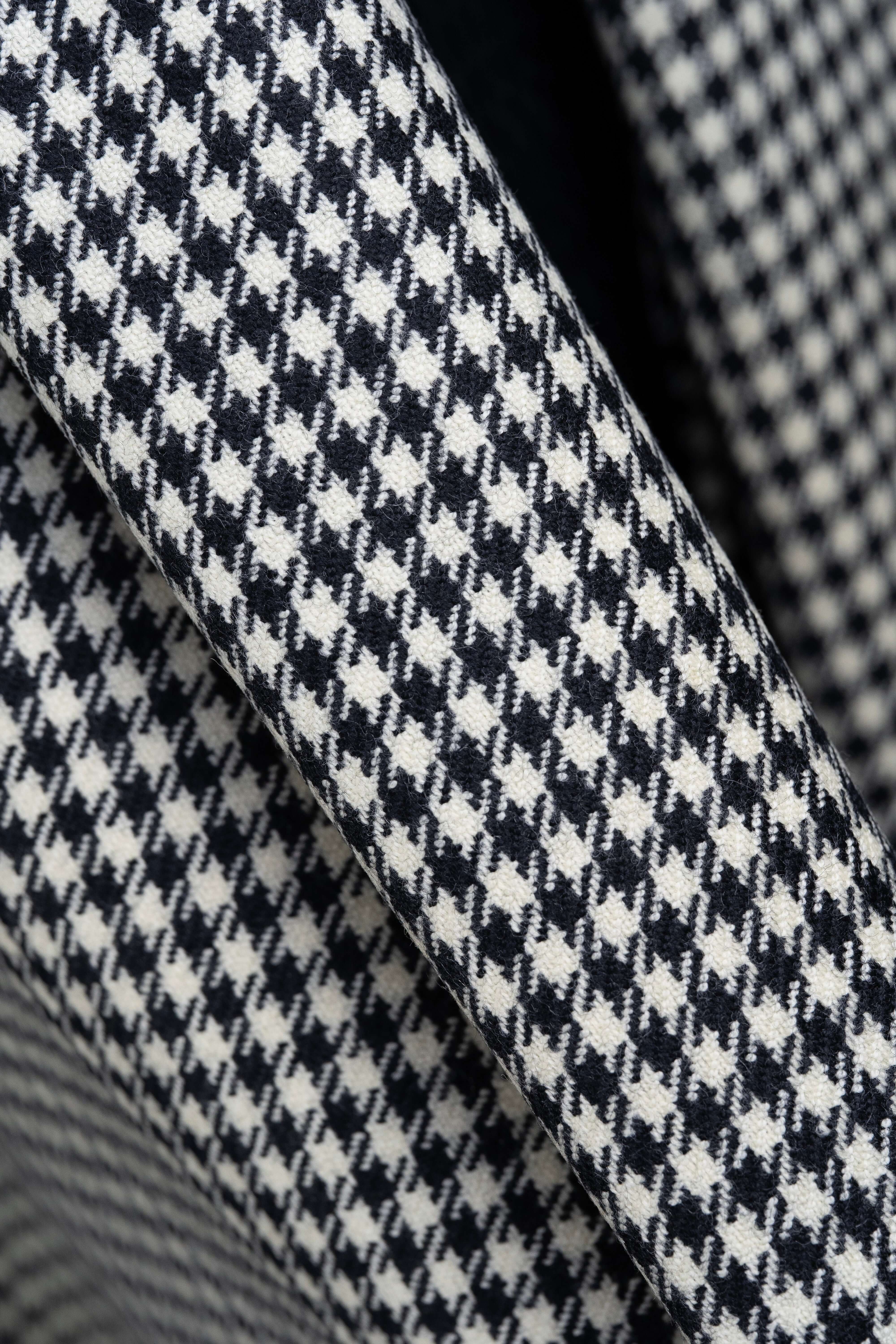 Close-up of houndstooth wool jacketing fabric showing intricate pattern and texture.