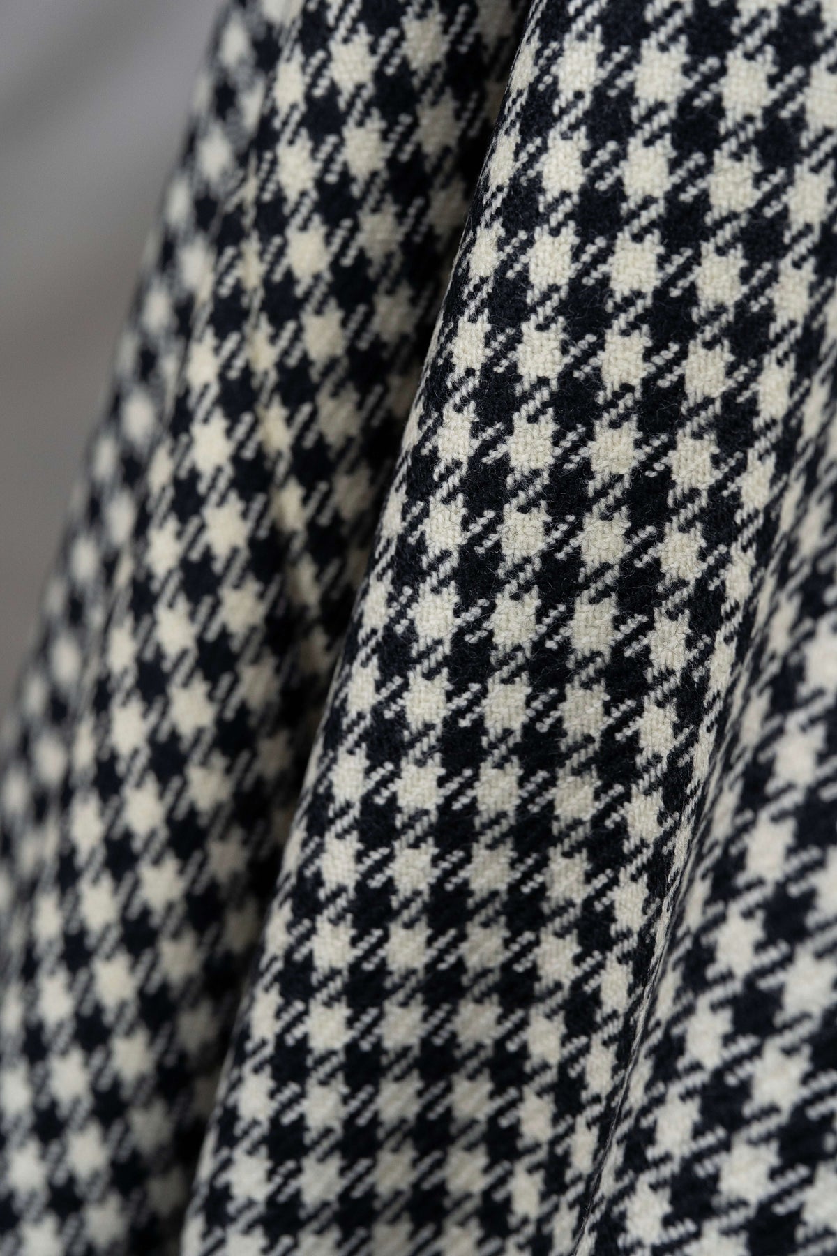 Close-up of houndstooth wool jacketing fabric showcasing its distinct black and white pattern.