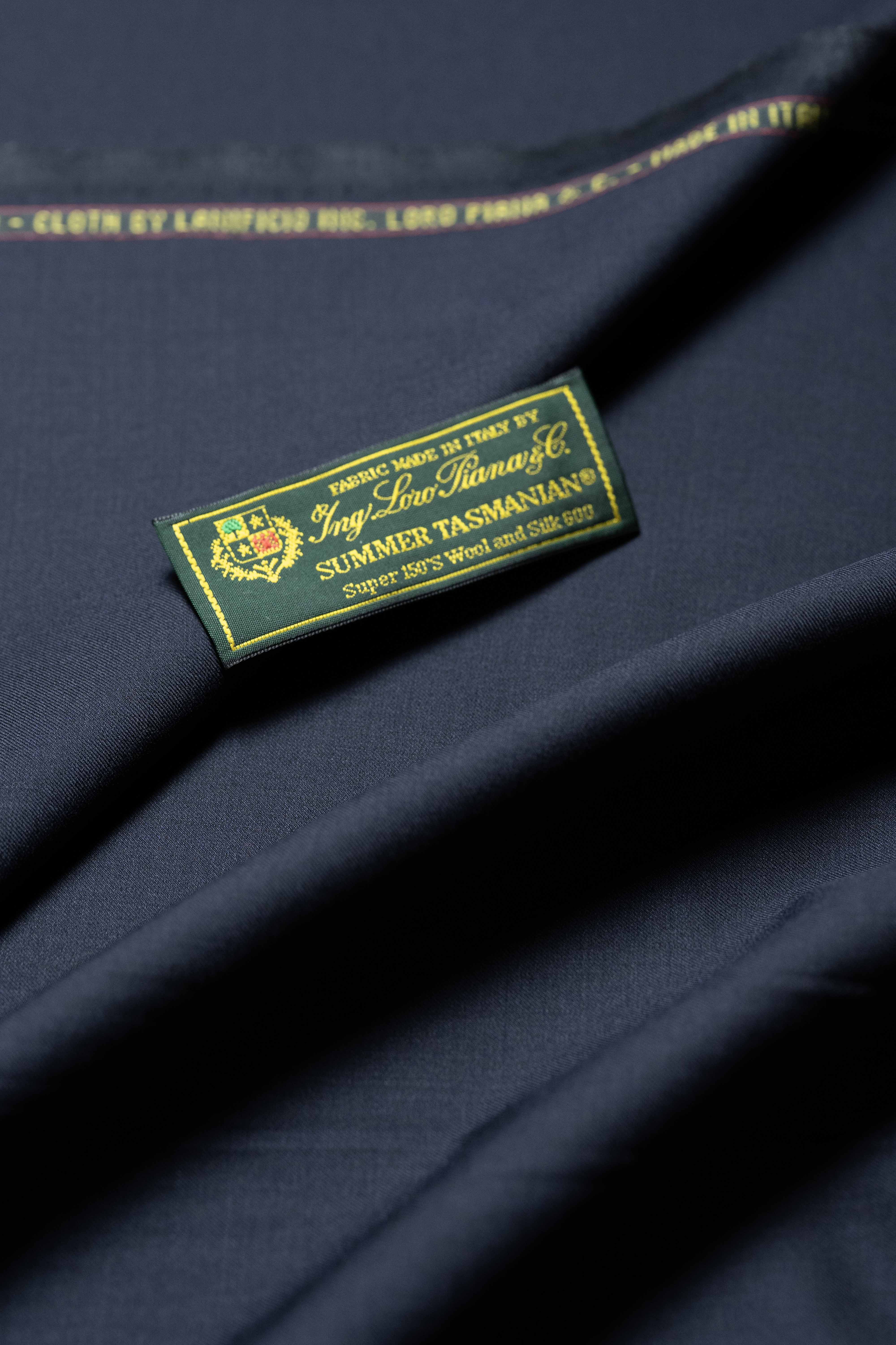 Loro Piana Midnight Navy Tasmanian 150's wool and silk fabric with label, showcasing luxury and sophistication.