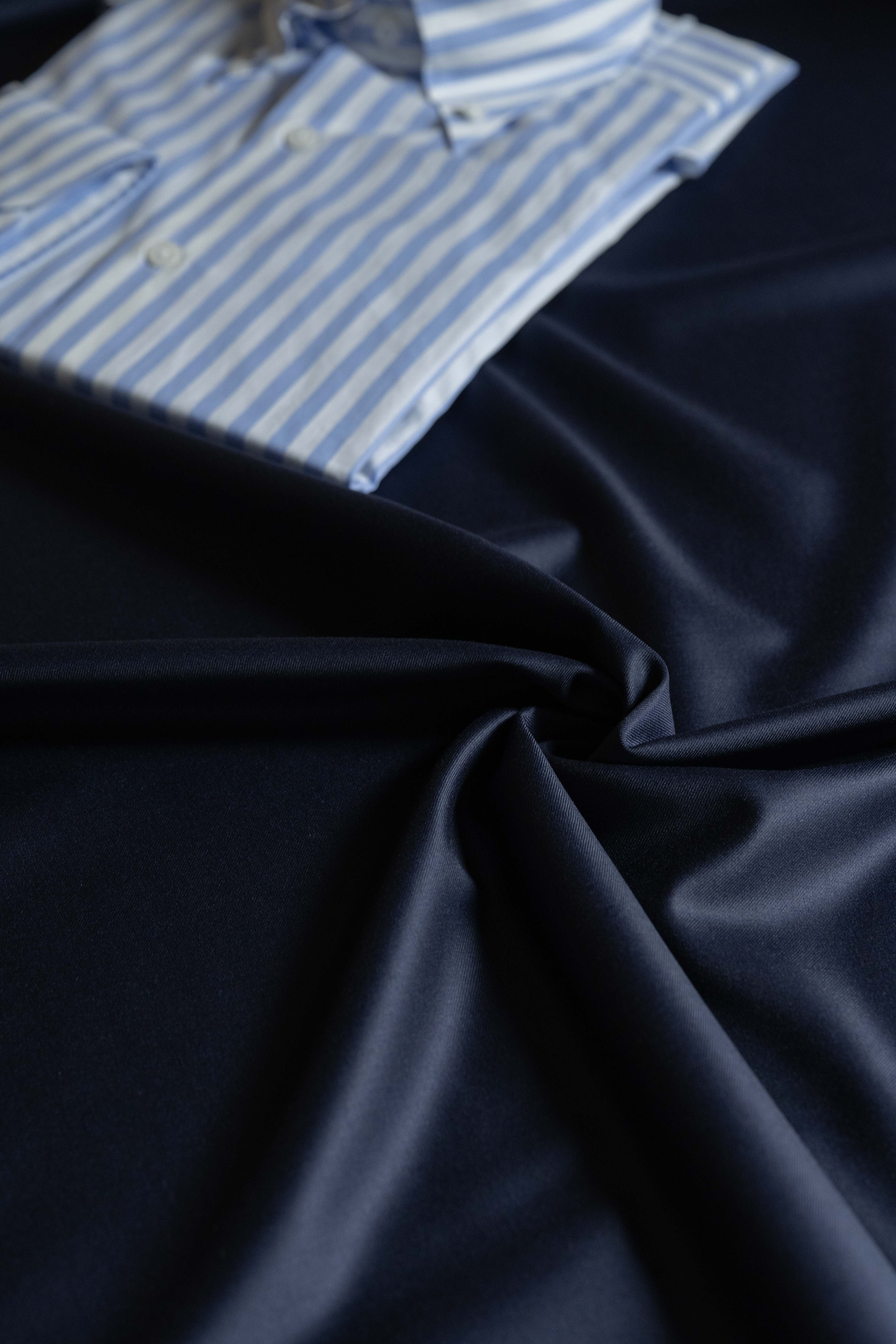 Loro Piana Dark Navy 150's Merino Wool Suit Fabric paired with a blue and white striped shirt.