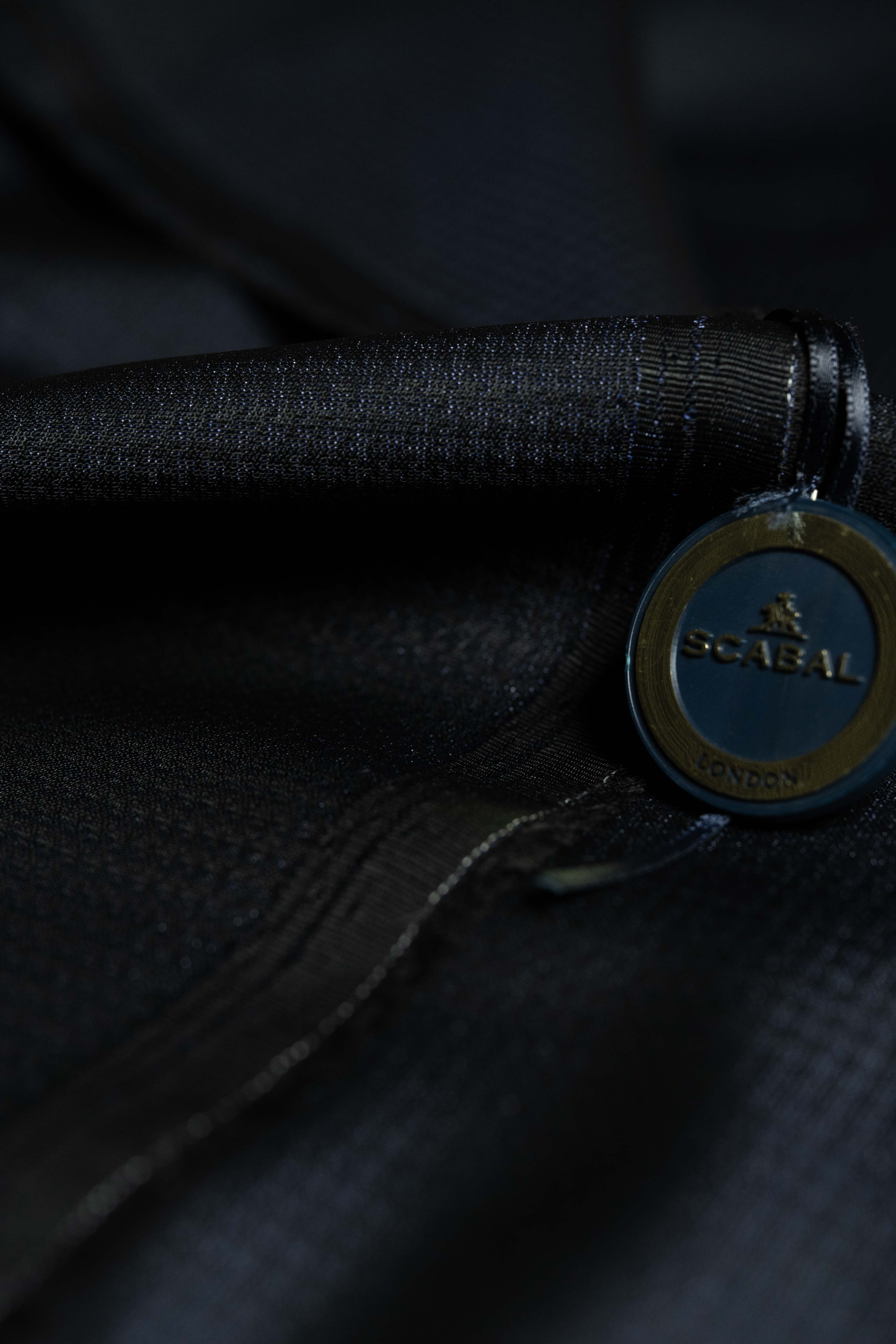 Close-up of Scabal dark navy festival collection fabric with branded tag.