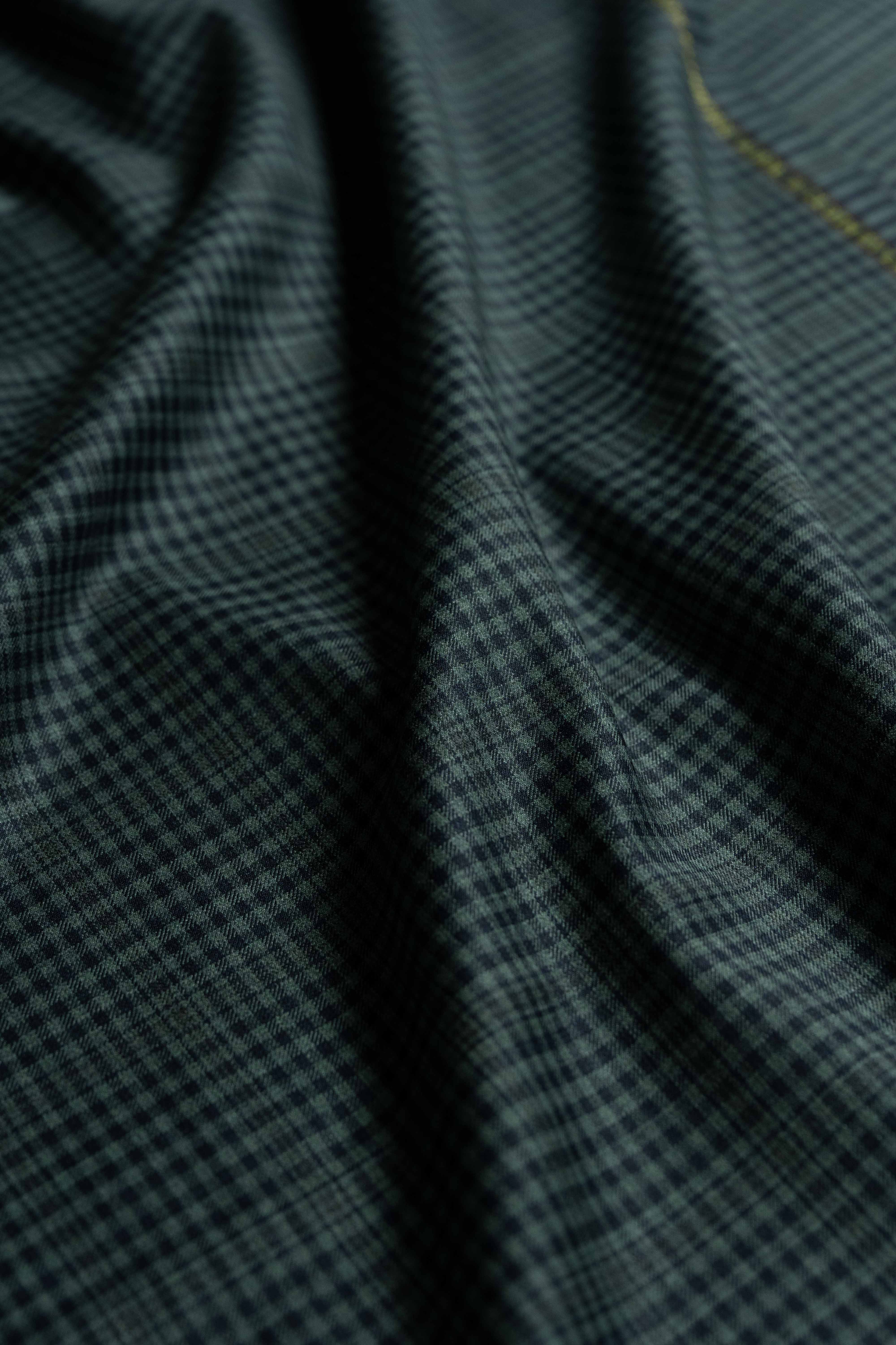 Loro Piana dark teal wool fabric with a checked pattern, showcasing its luxurious texture and quality craftsmanship.