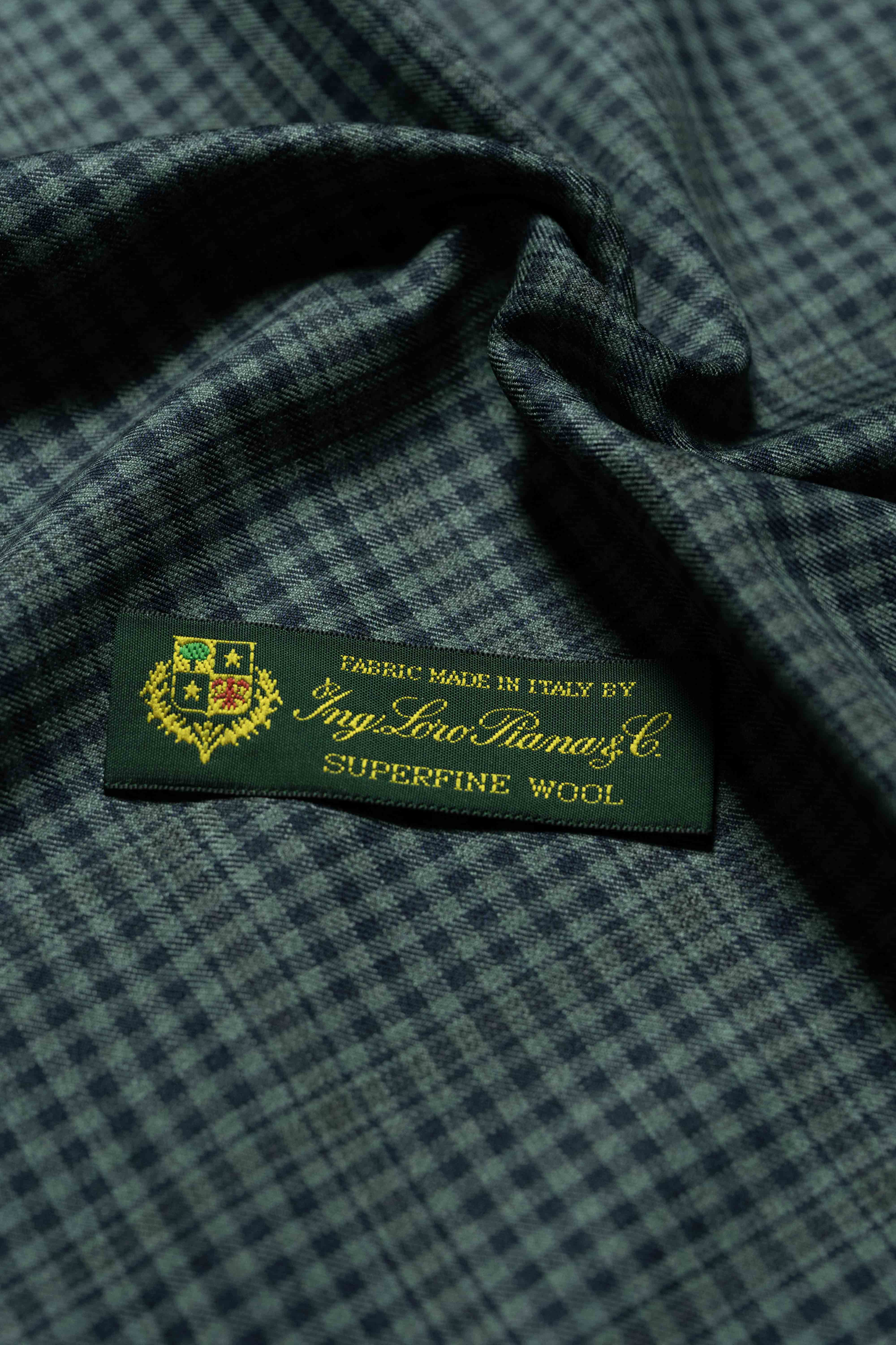 Loro Piana dark teal wool fabric, showcasing the tag indicating it is made in Italy with superfine wool.