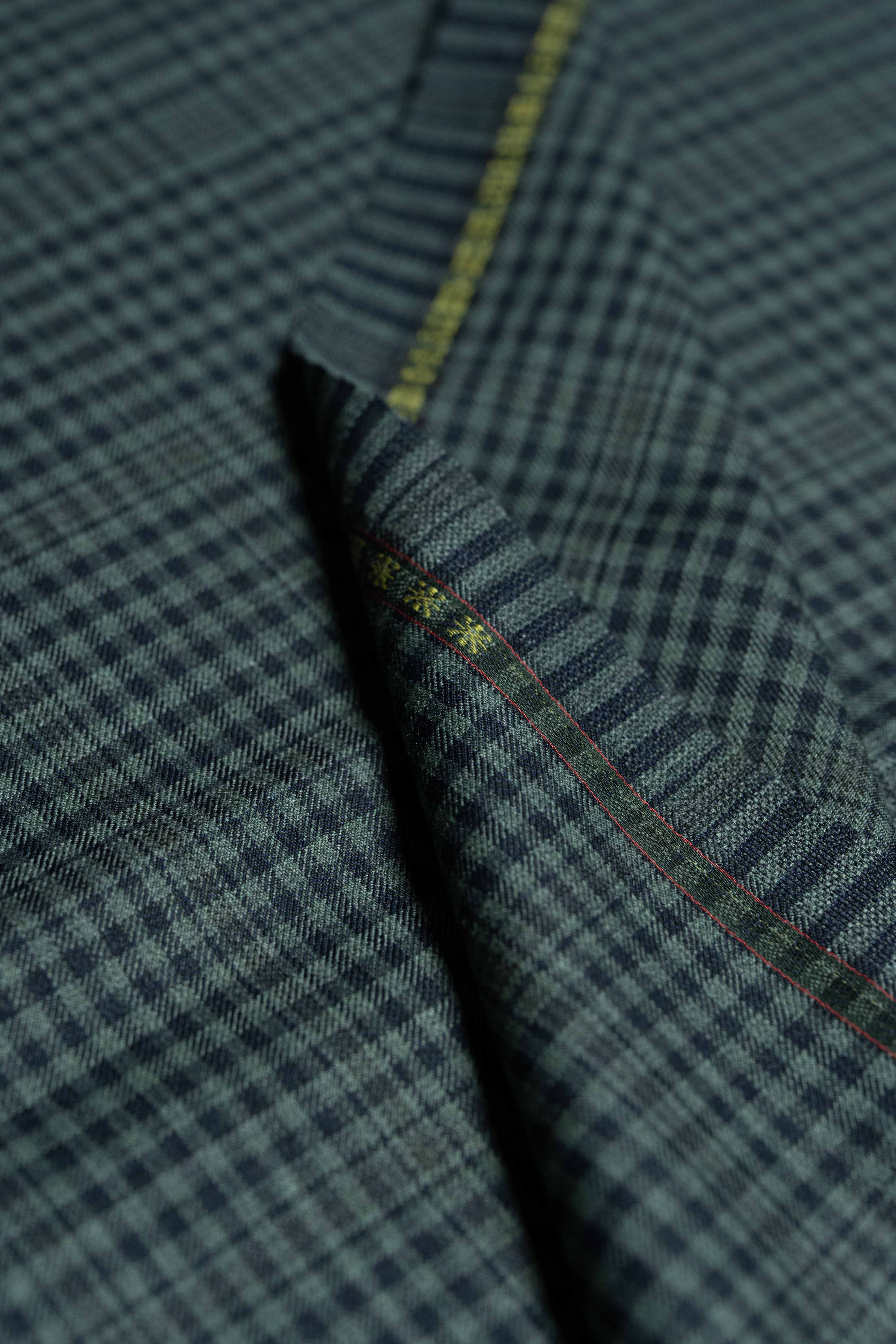 Loro Piana dark teal wool fabric with intricate pattern and detailing, perfect for luxury tailoring.