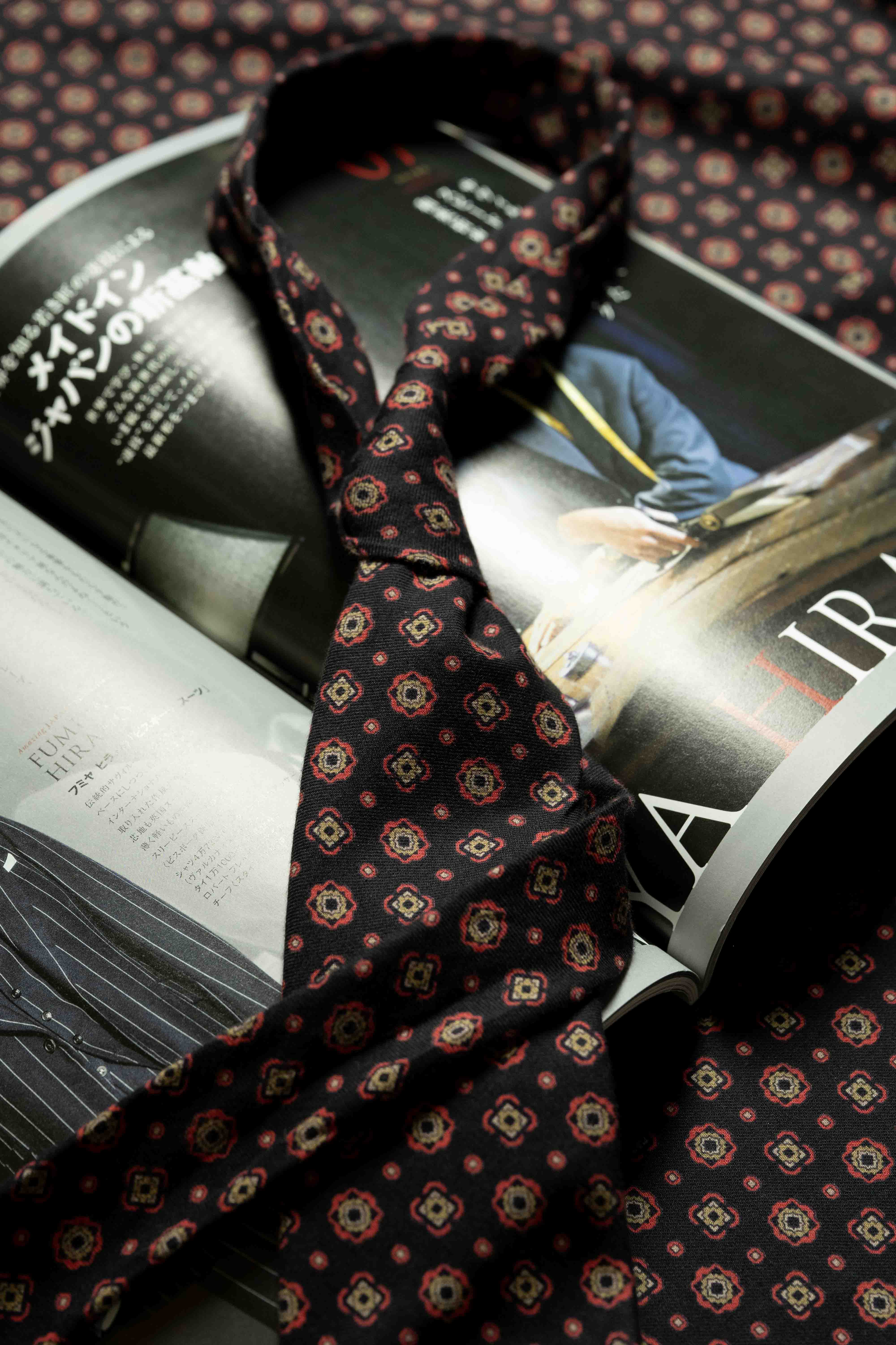 Vintage fabrics tie draped over a magazine, showcasing the rich patterns and colors of textile designs.