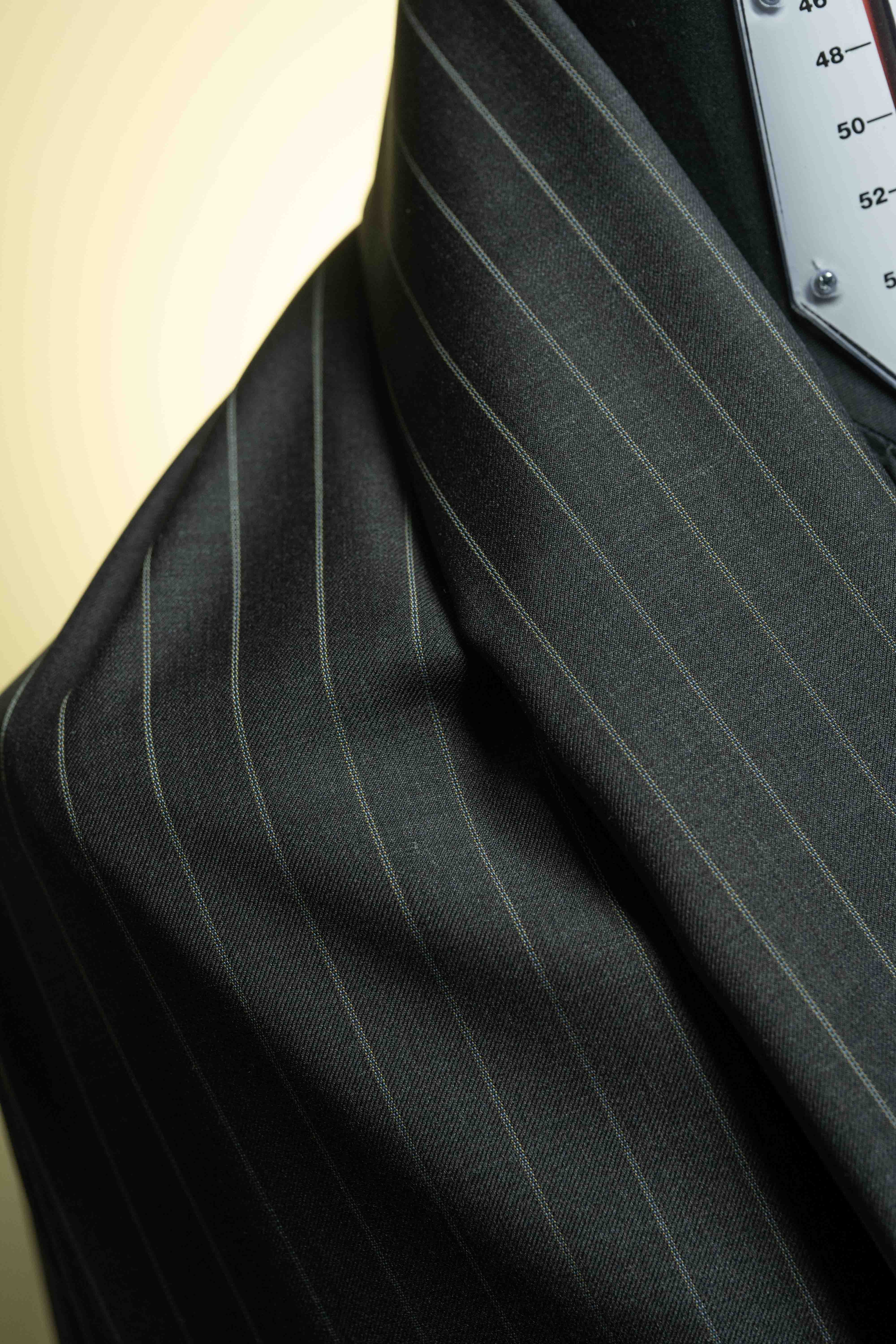 Close-up of charcoal stripe fabric from a 150's & cashmere suiting, showcasing its texture and pattern.