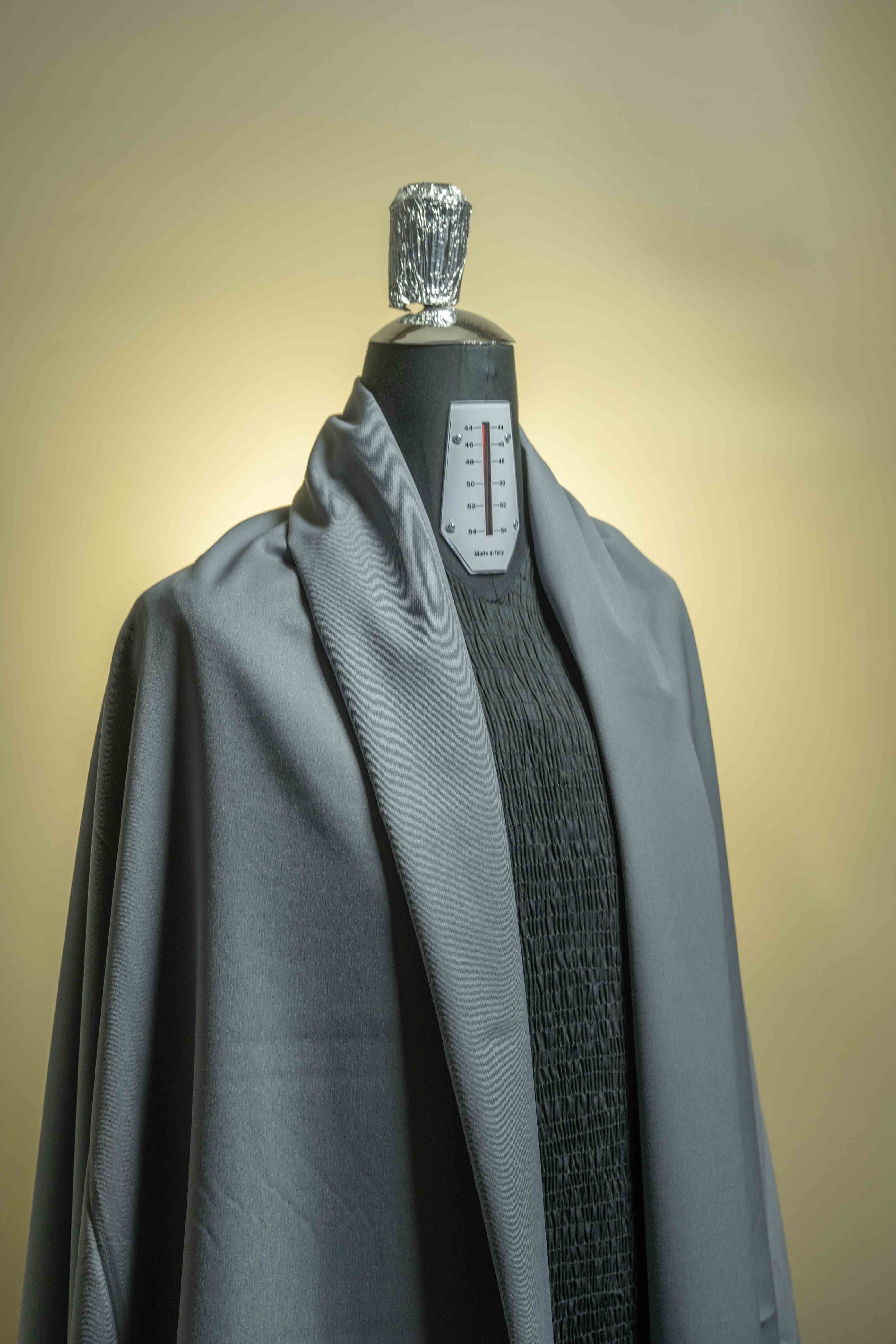 Grey 120's wool gabardine suit fabric displayed on a dress form, showcasing its elegant texture and color.