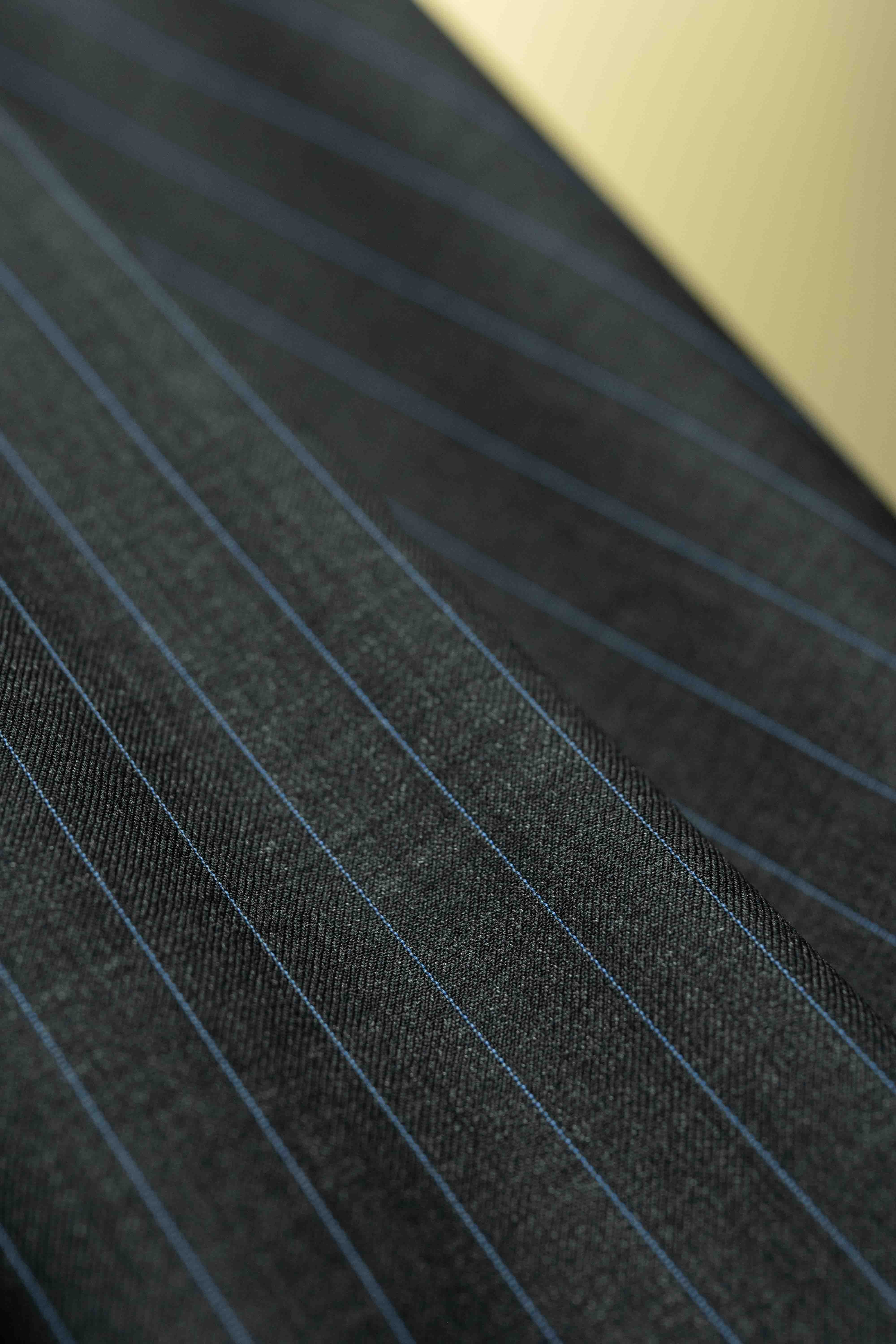 Close-up of charcoal blue stripe fabric for cashmere suiting, highlighting the quality and texture of the material.