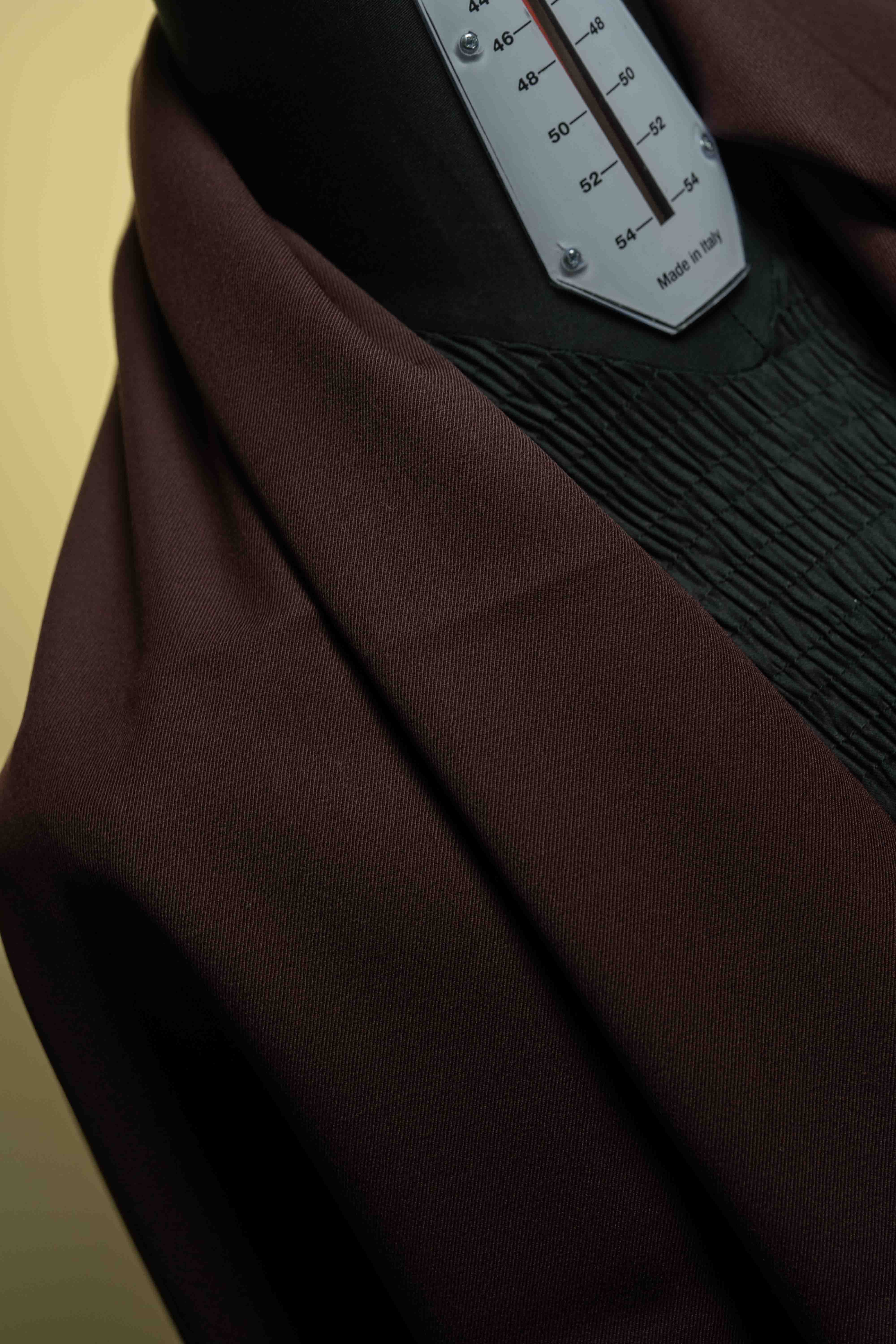 Close-up of red mink cashmere suit fabric draped on a mannequin for stylish trousers.