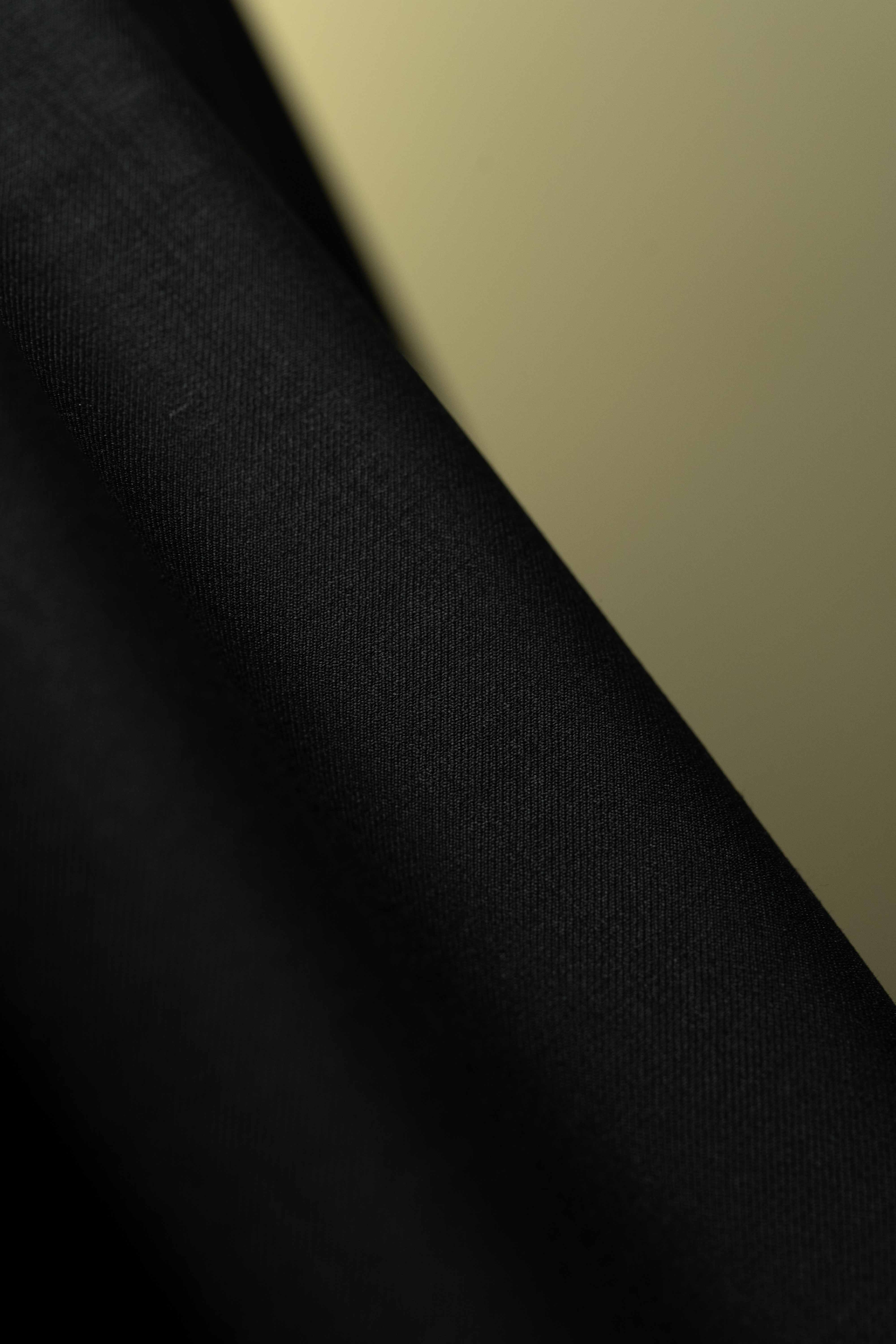 Close-up of luxurious Black Merino Cashmere wool with silk fabric for suit jacket.