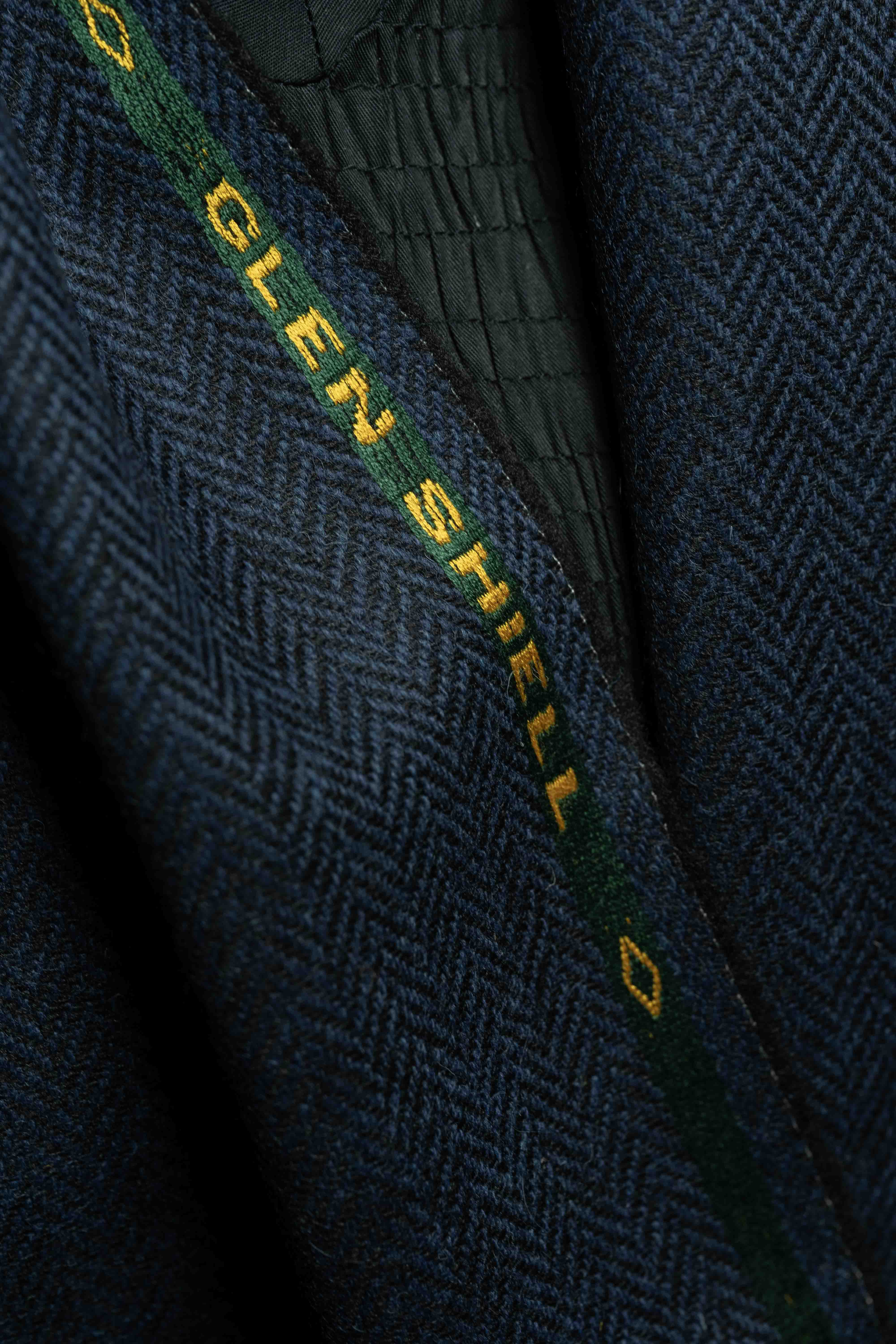 Navy herringbone wool suit fabric interior detail, showing texture and label on jacket.