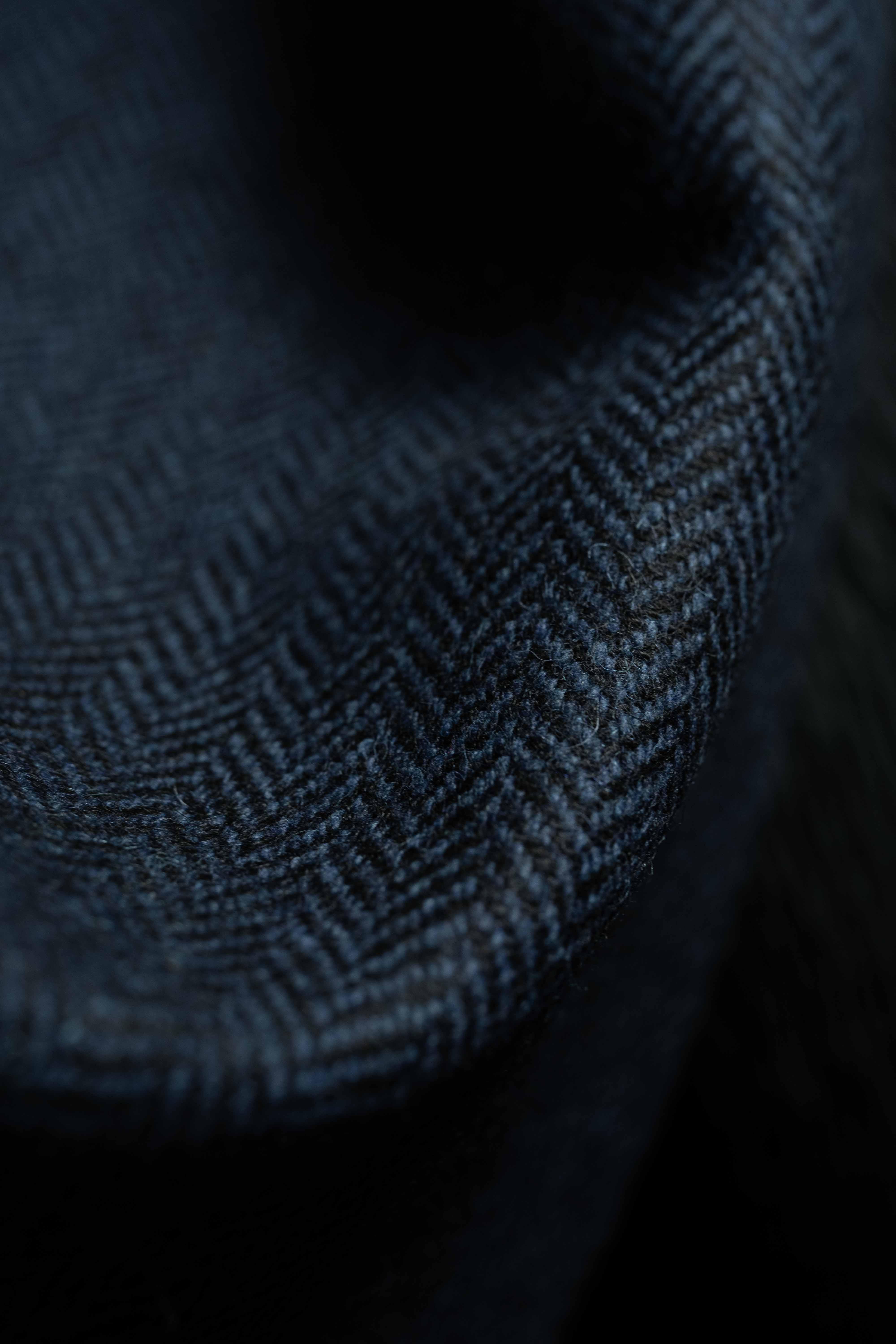 Close-up of navy herringbone wool suit fabric showcasing intricate weave details.