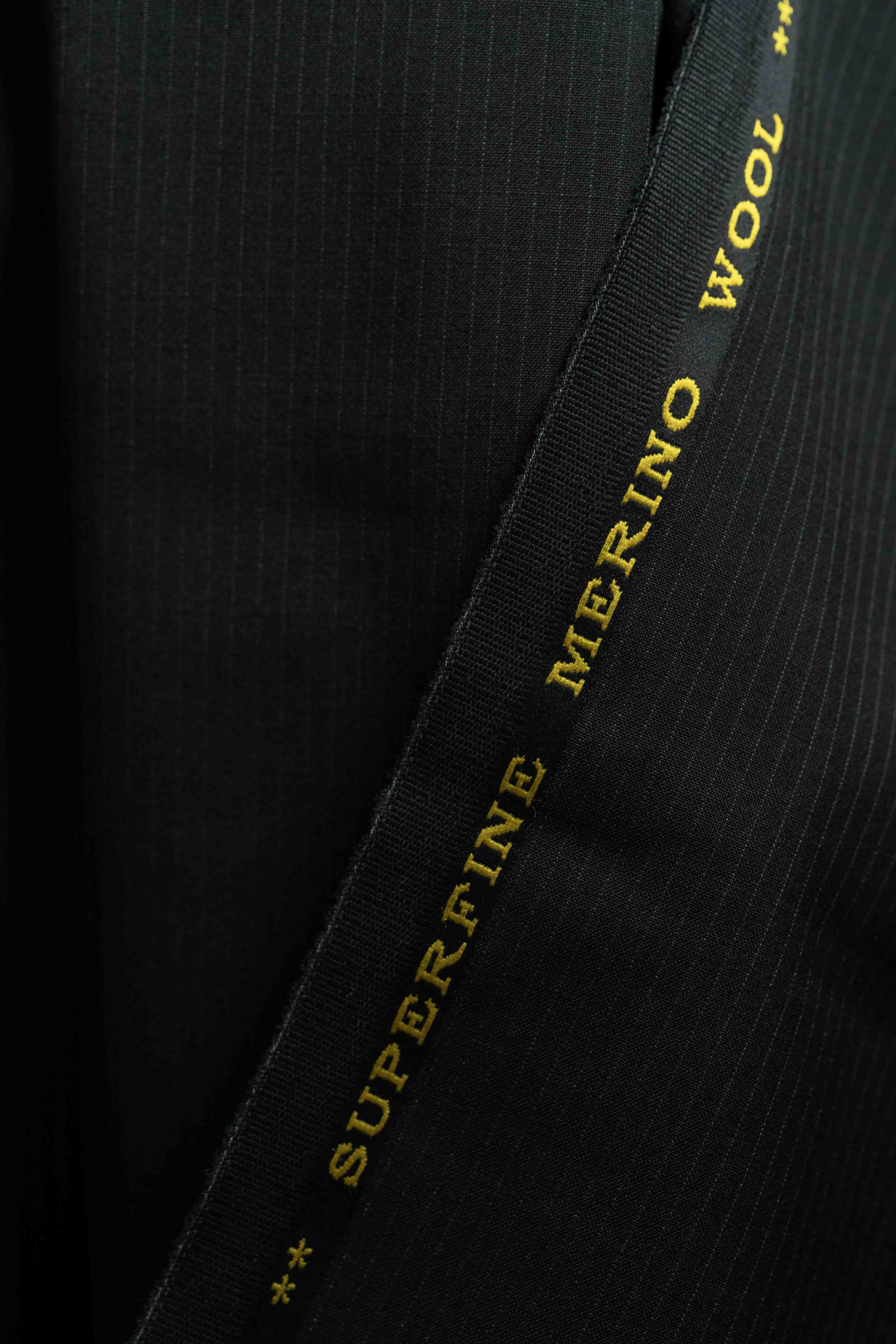 Reda Black Stripe Merino Wool Suit Fabric detail with "SUPERFINE MERINO WOOL" label.