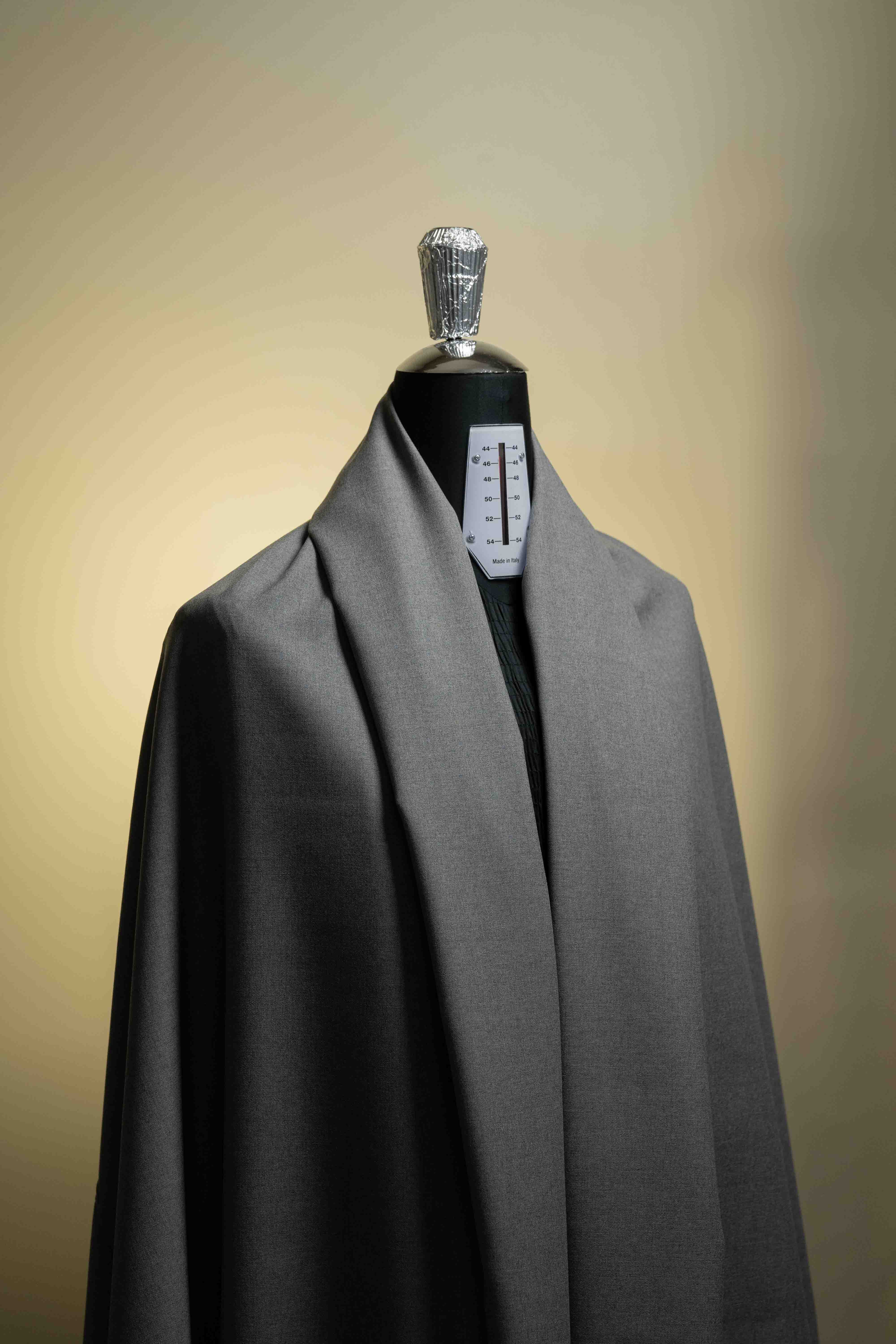 Gray coat on a mannequin against a plain background