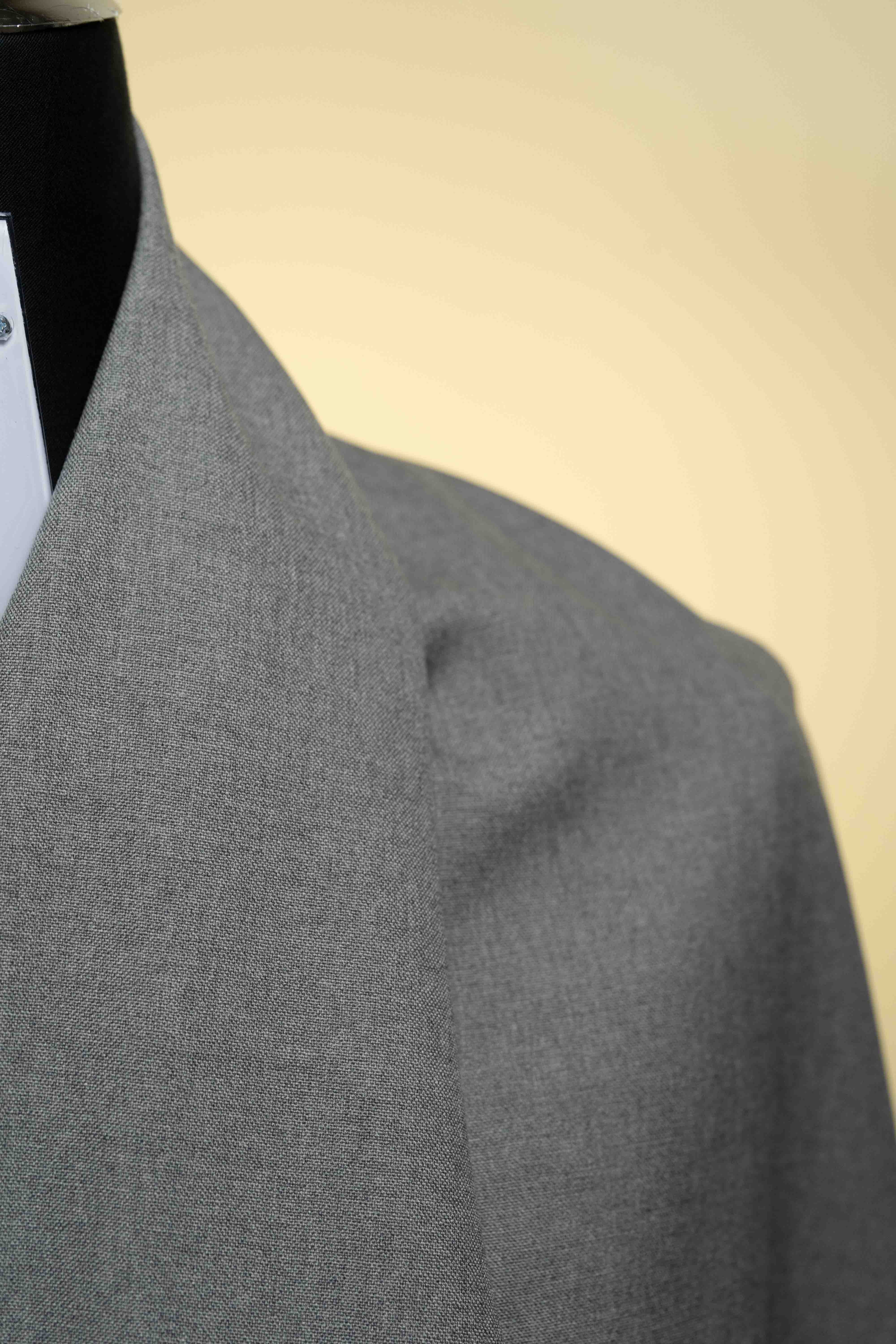 Gray coat on a mannequin against a beige background