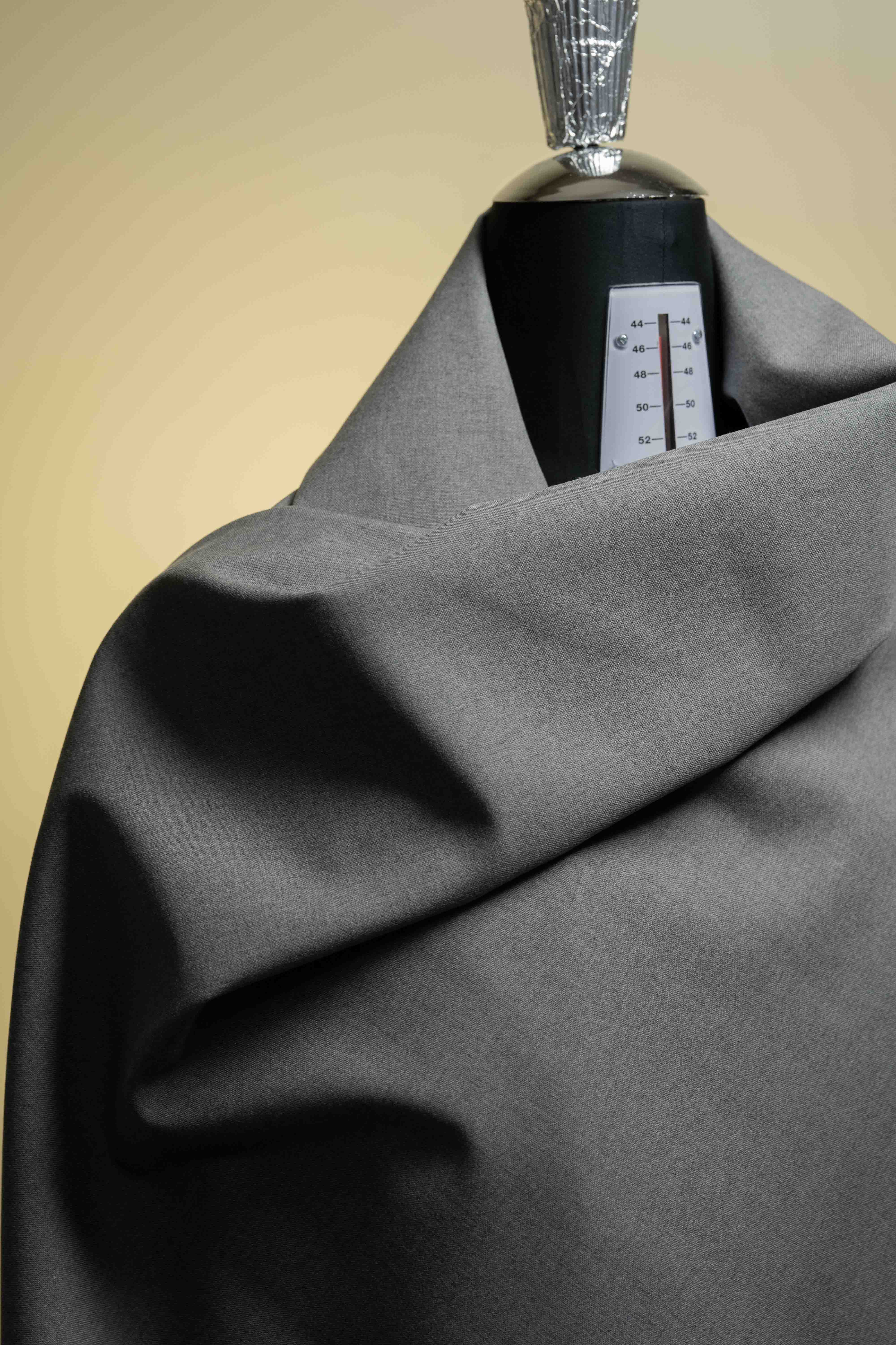 Gray fabric with a black rectangular object and a silver cap on a beige background