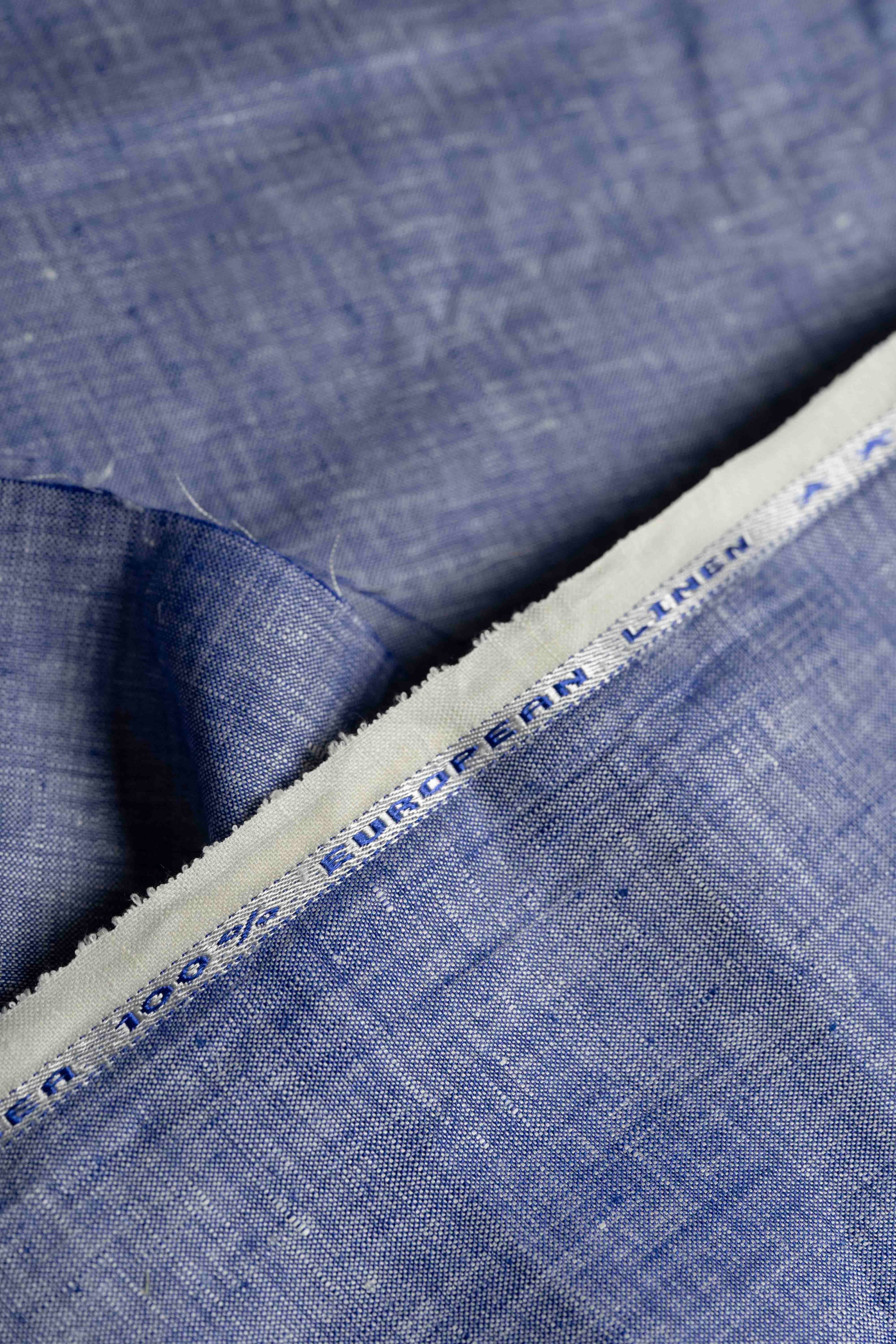 Close-up of blue linen fabric with a brand label.